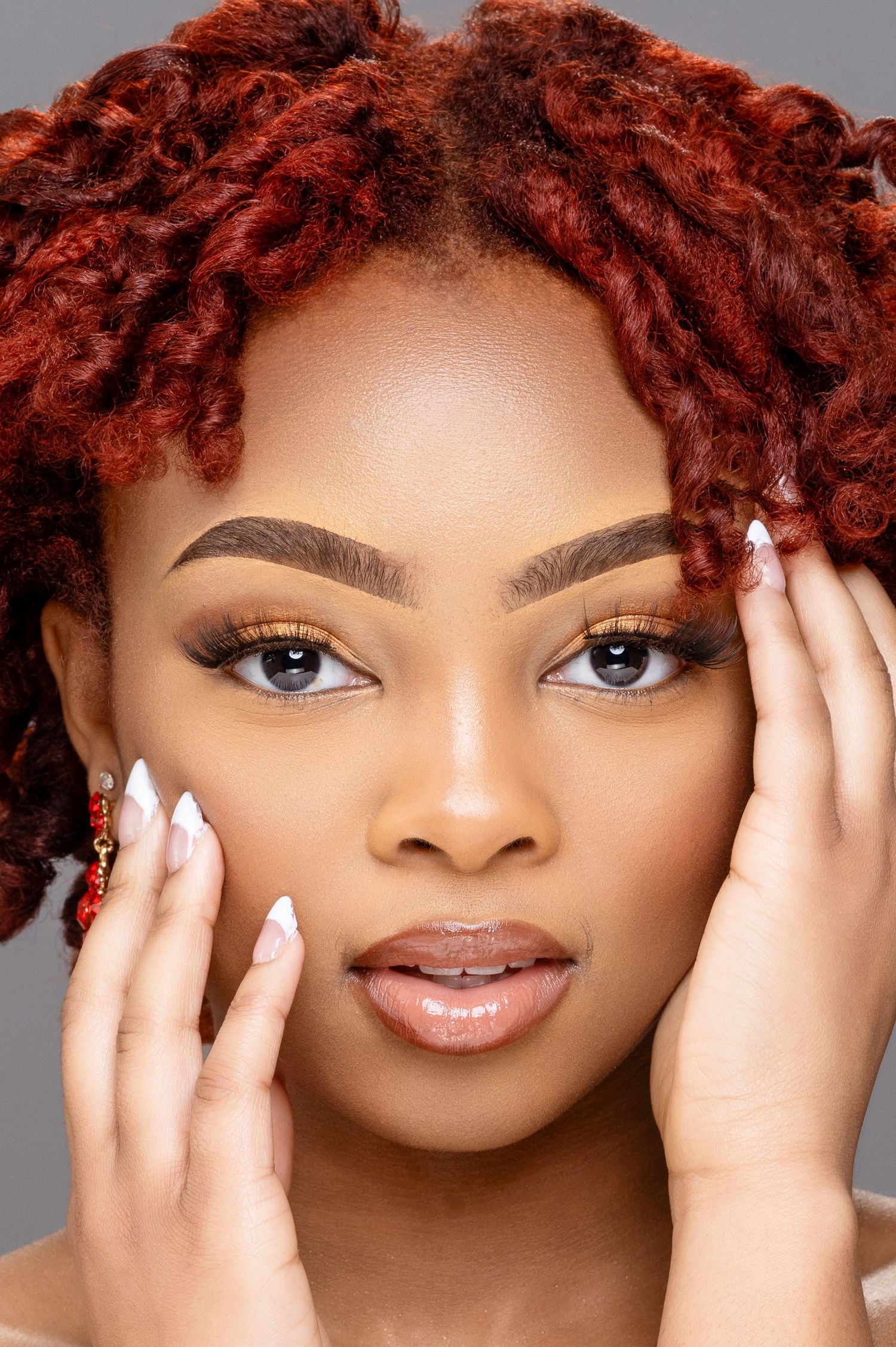 A series of close-up beauty shots featuring bright red curly hair, flawless makeup, and elegant manicured nails.