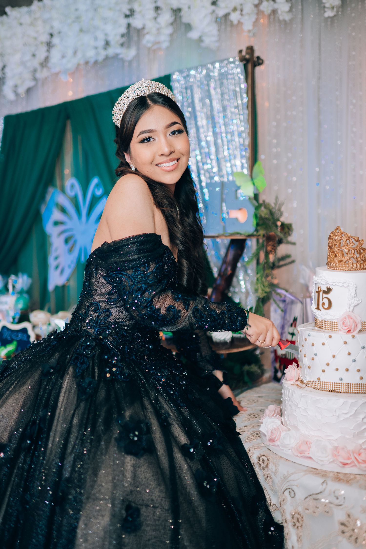 A celebration features an elegant black ballgown, sparkling tiara, and decorative multi-tiered cake against a teal backdrop.