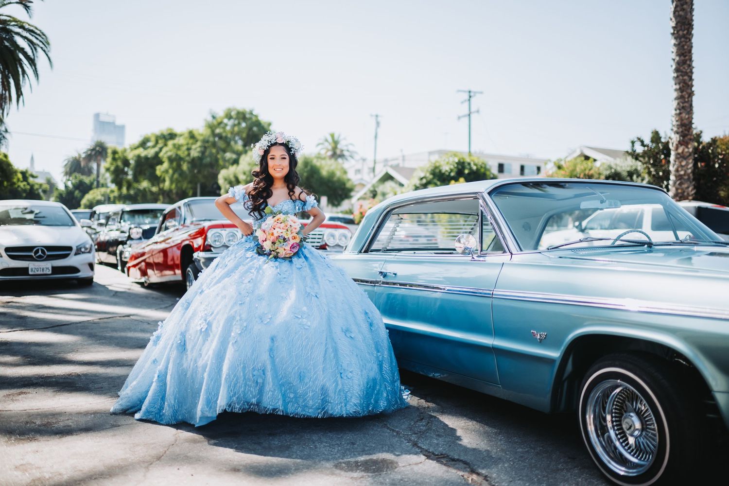 Magical quinceañera photo featuring a blue ball gown posed with classic vintage cars.