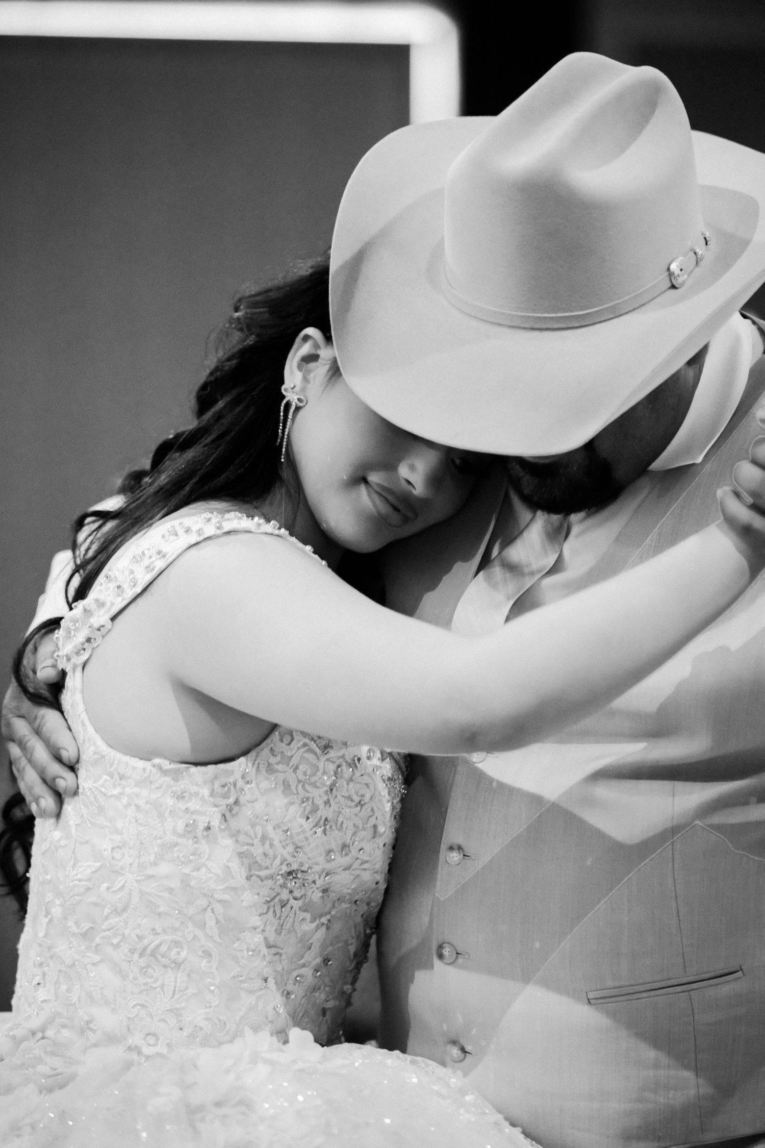 Black and white romantic moment with white cowboy hat and wedding attire.