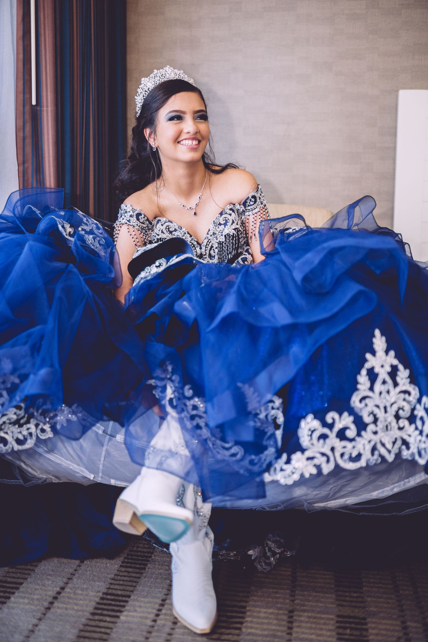 A royal blue quinceañera dress with intricate white lace details sparkles in natural light.
