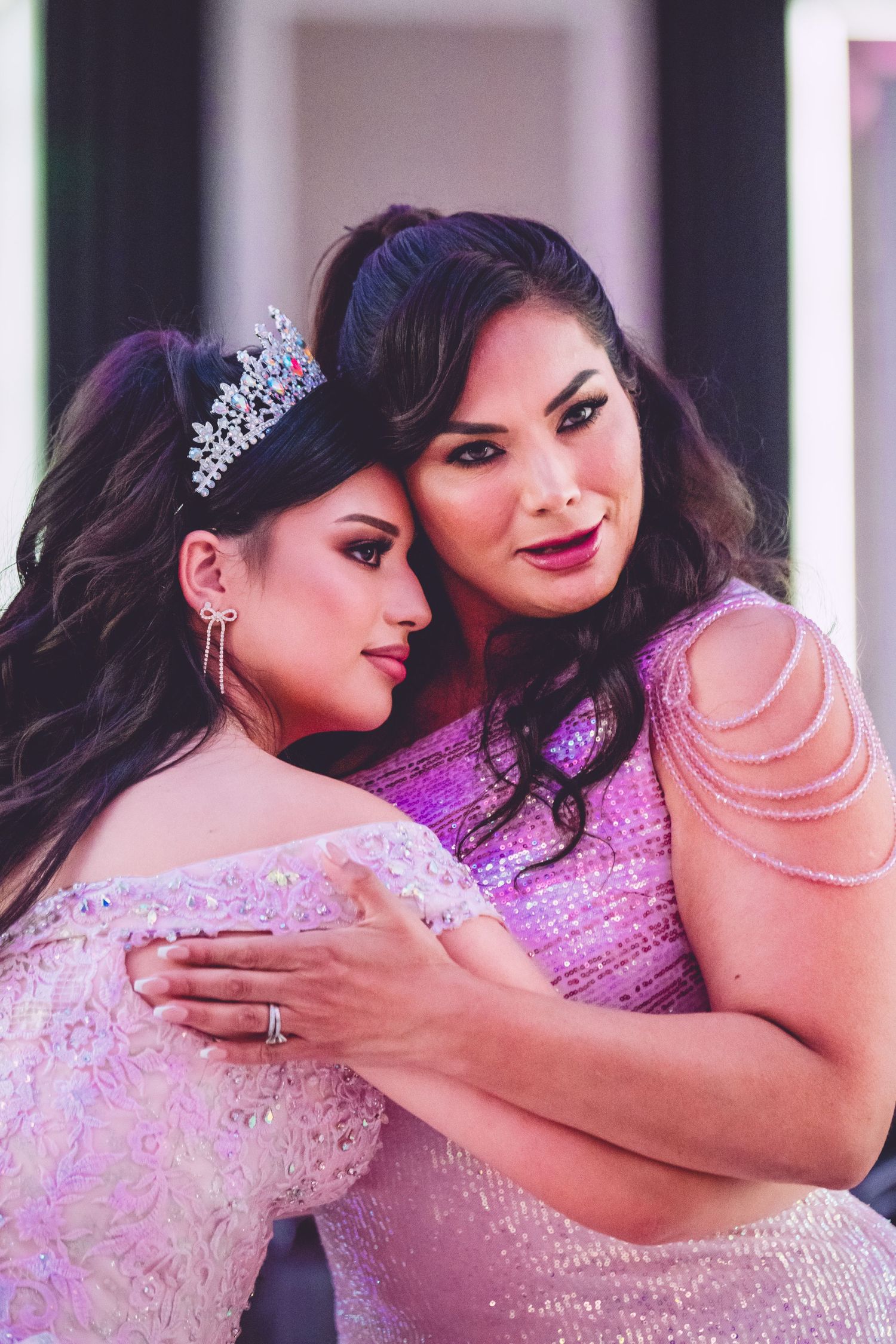 Intimate portrait of two people in pink formal wear and tiaras.