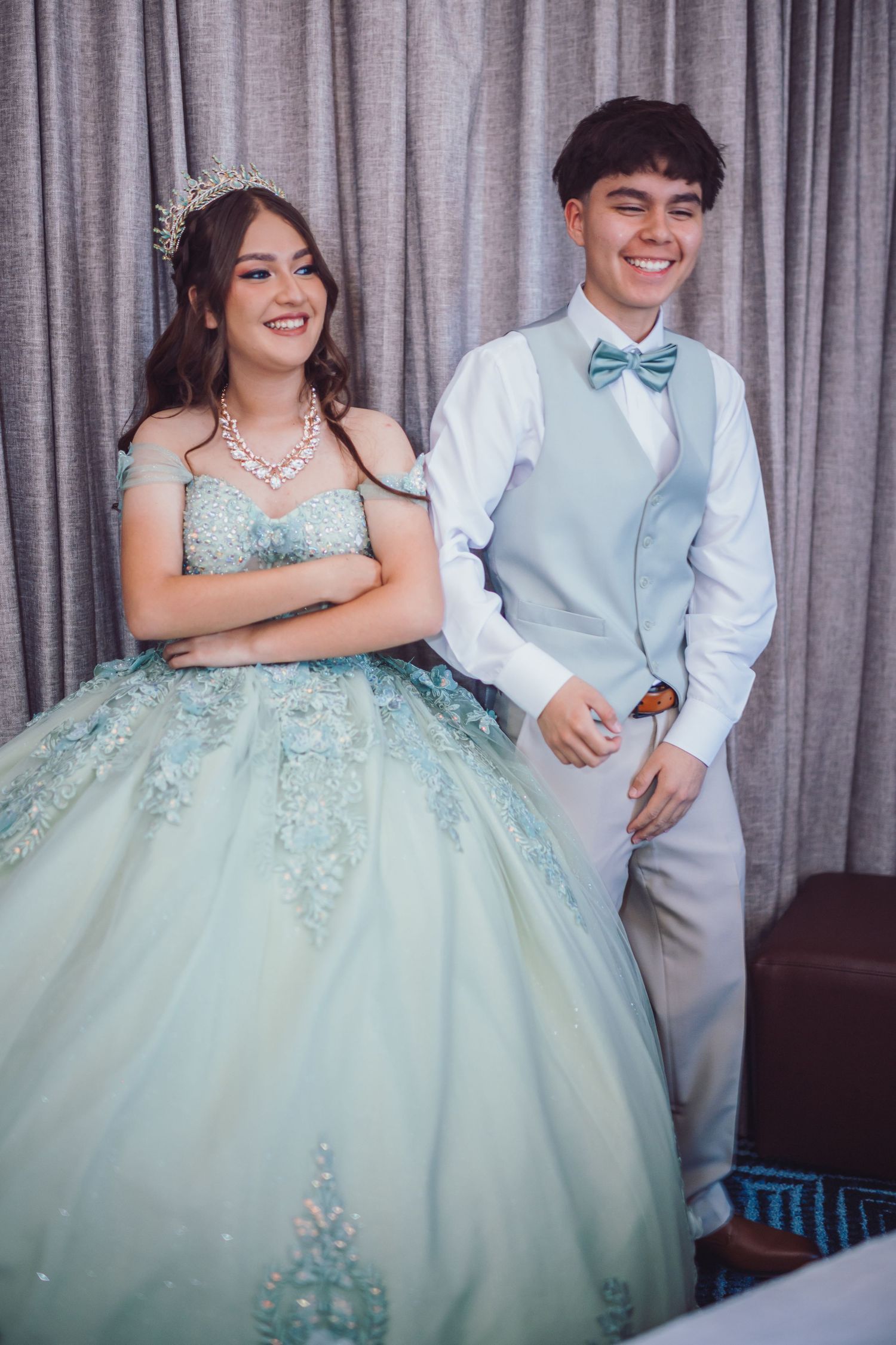 Young couple in formal attire, girl in mint green ball gown with tiara, boy in light blue suit with bow tie.