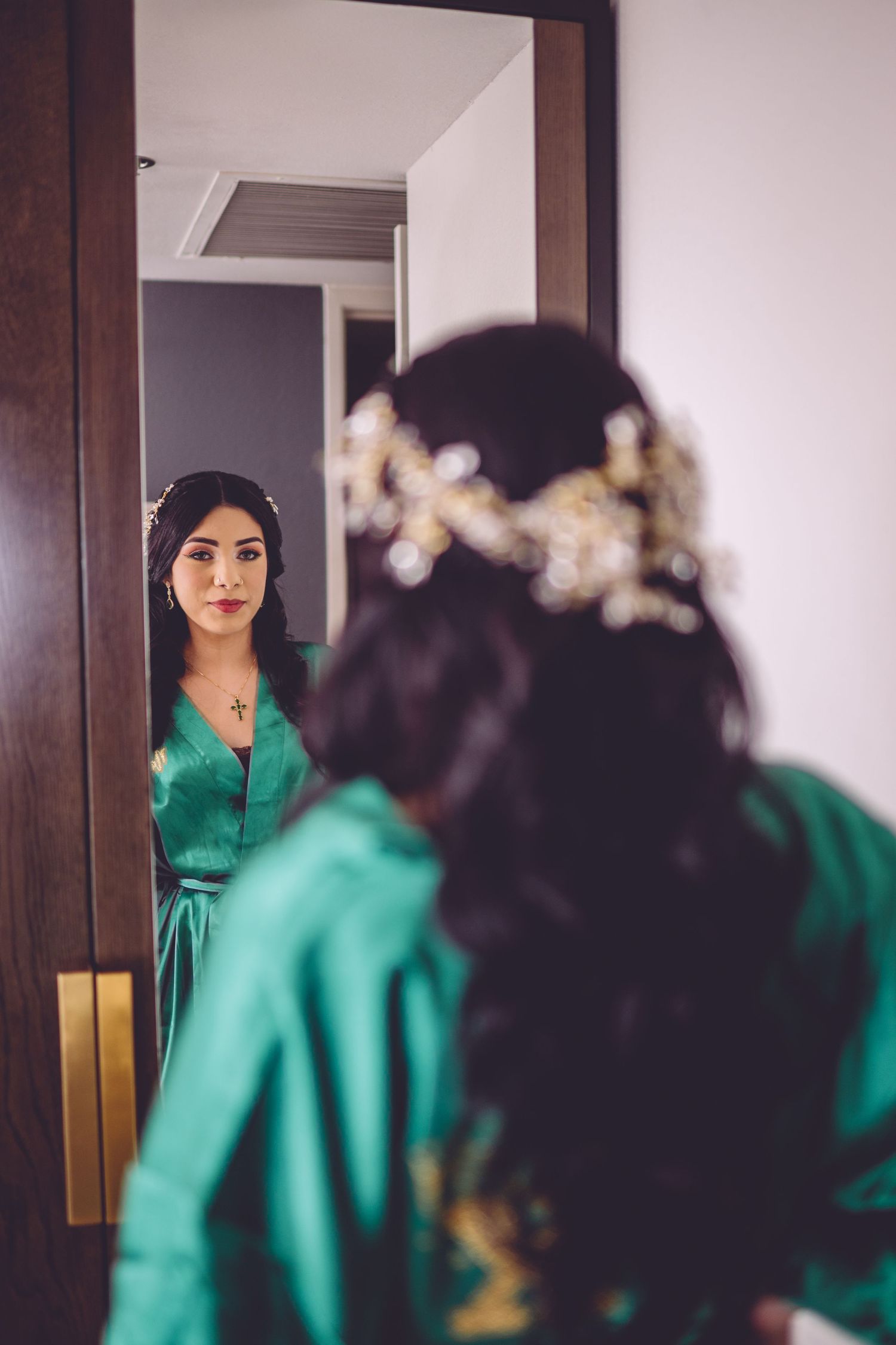An emerald green silk robe reflects in a mirror during preparation time.