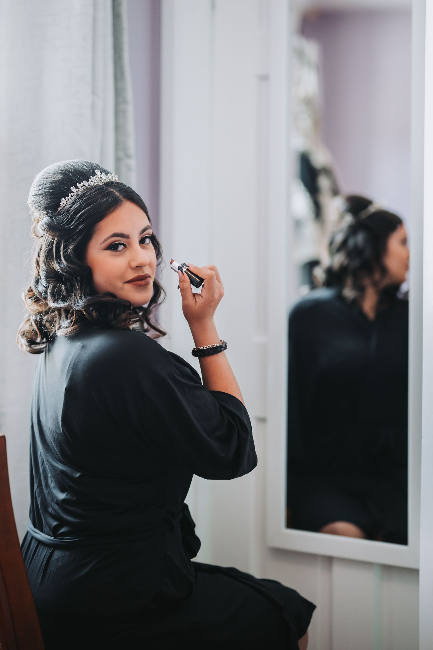 An elegant makeup preparation scene with a tiara and black robe reflected in the mirror.