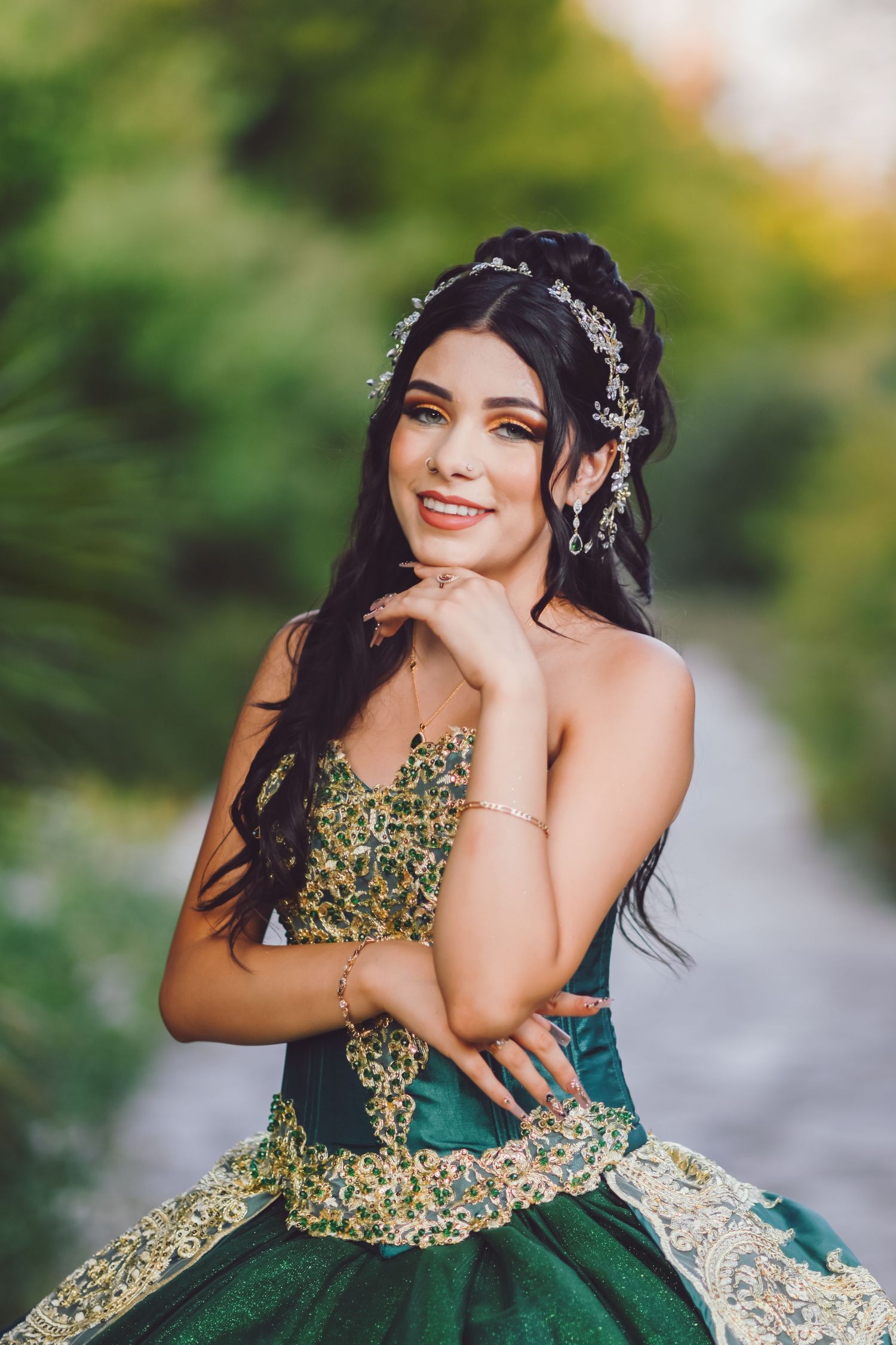 Stunning emerald ballgown with gold embellishments and sweetheart neckline in outdoor garden setting.