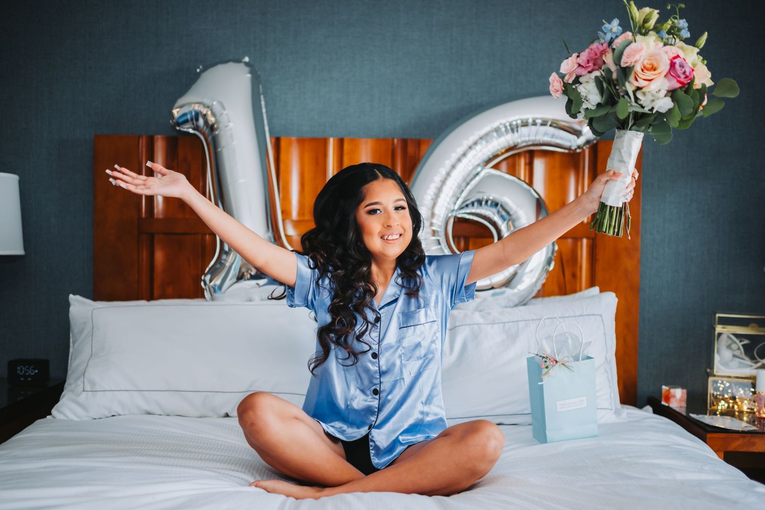 Silver number balloons and a bouquet decorate a bedroom celebration scene.