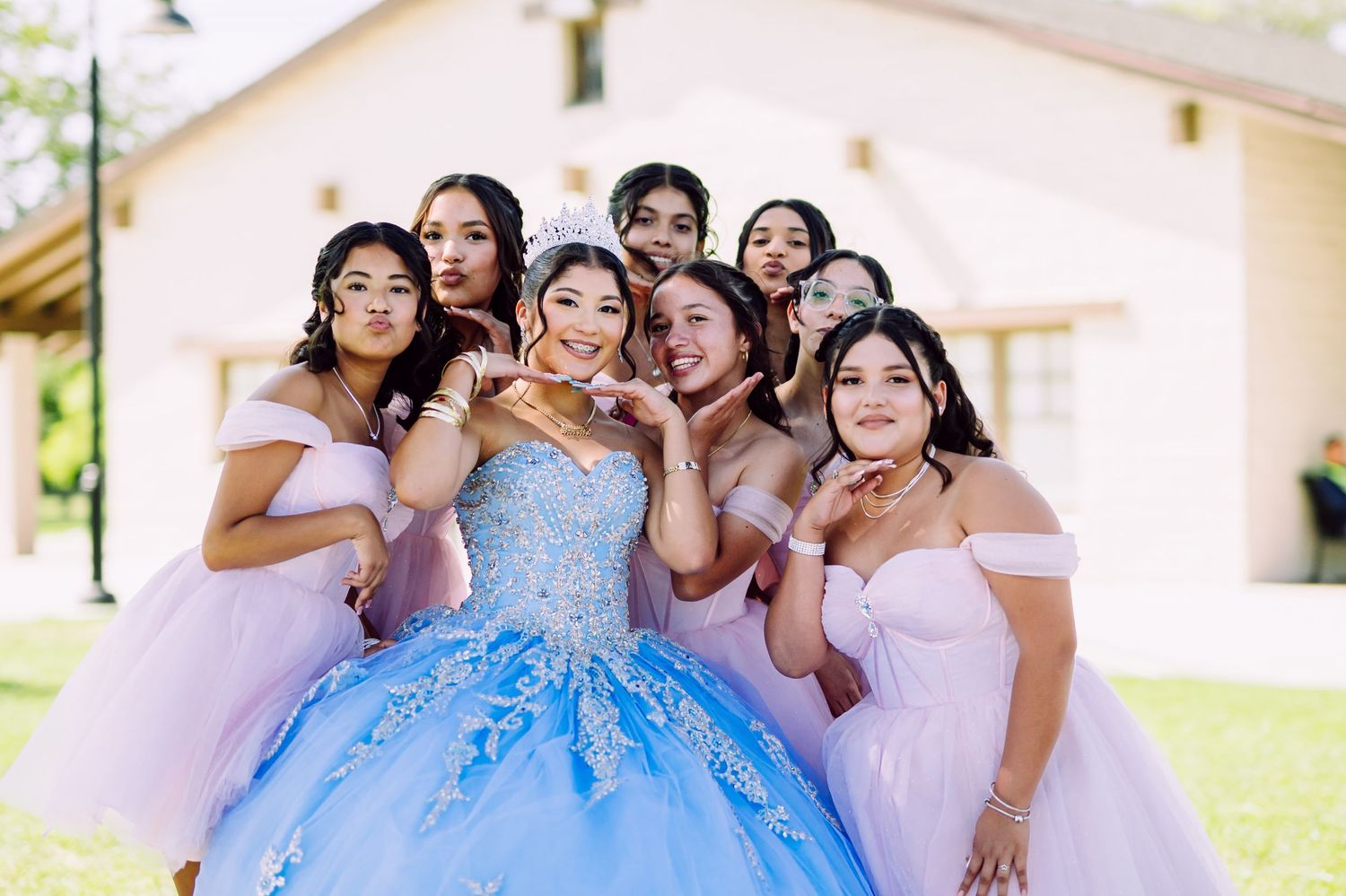 Friends in pastel gowns gather together outdoors for celebratory photos.