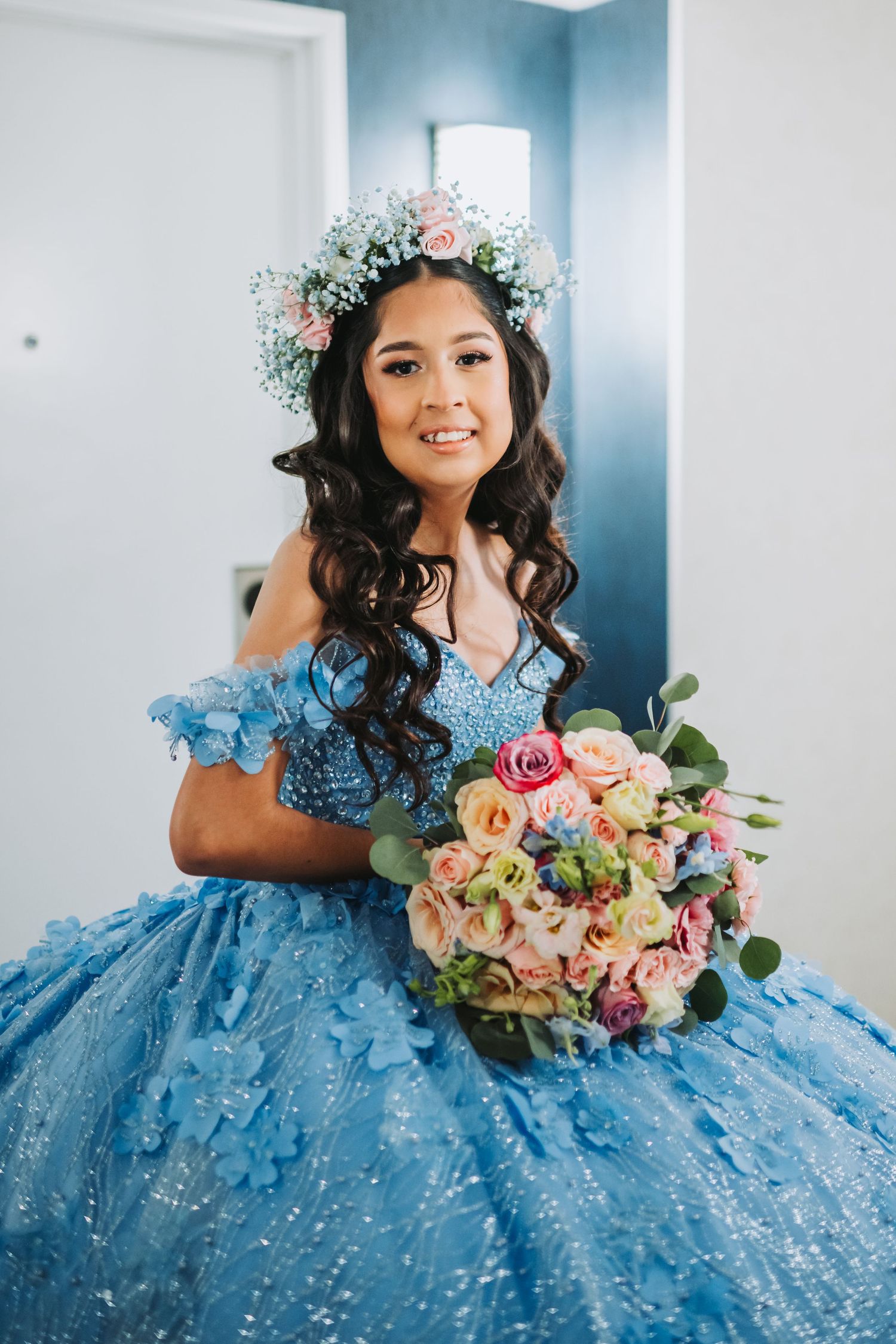 A beautiful blue ballgown and floral crown complement a stunning bouquet of pink and white flowers.