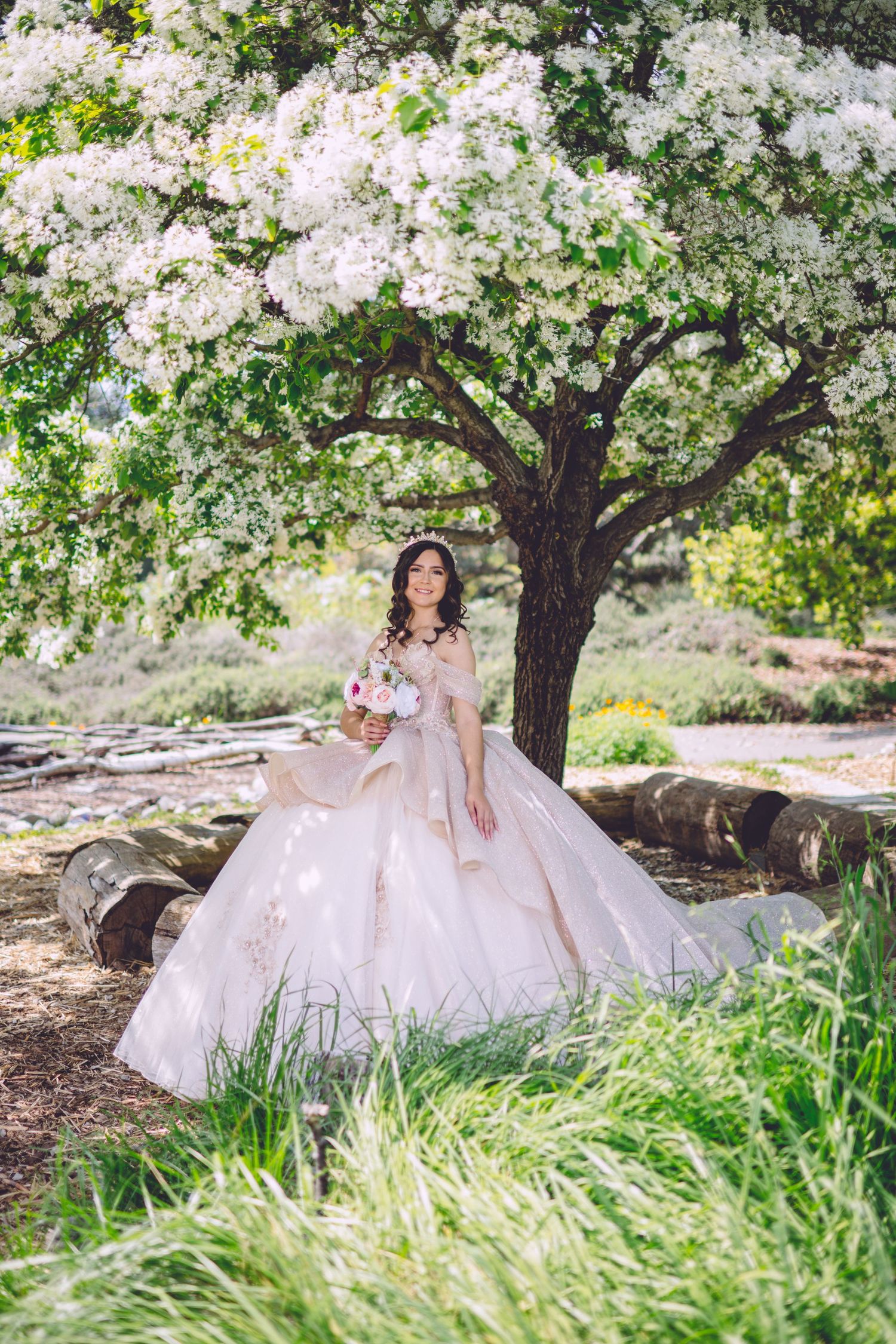 Romantic white ball gown under blooming cherry blossom tree in spring garden setting.