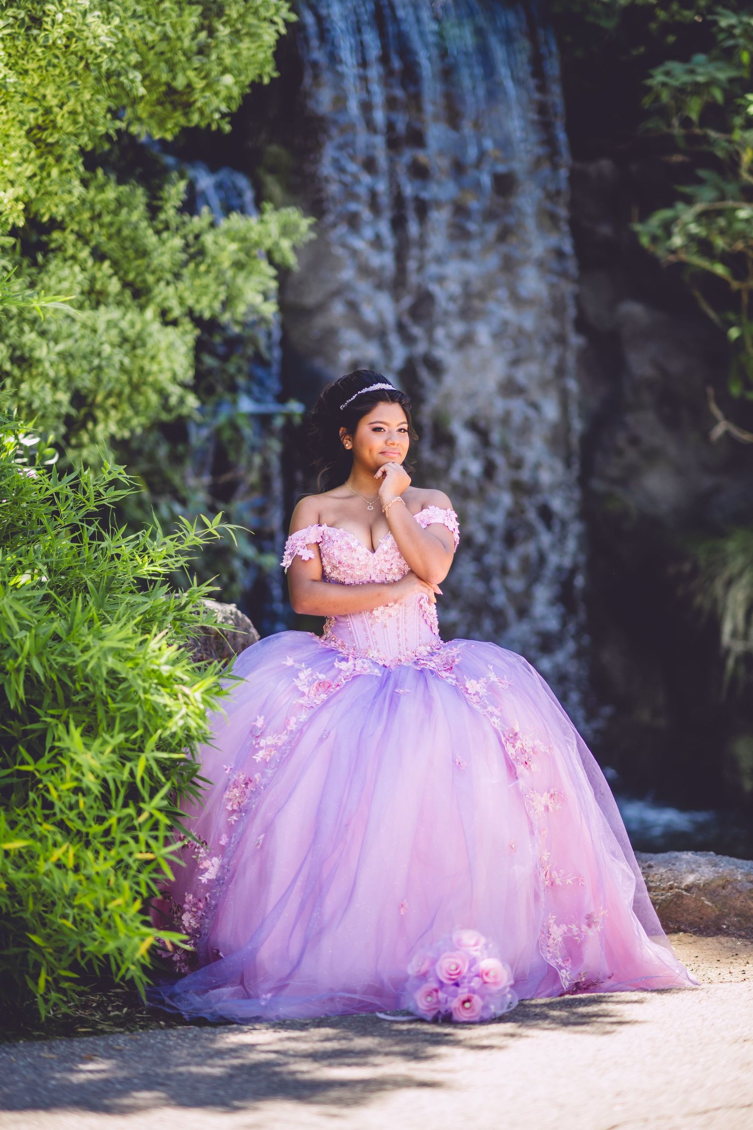 A magical scene with a lavender ball gown against a cascading waterfall and lush greenery.