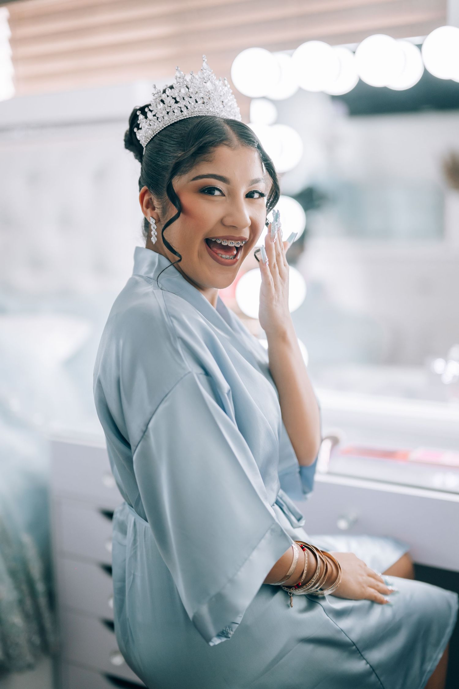 A joyful moment captured during wedding prep showing a blue robe and sparkling tiara.