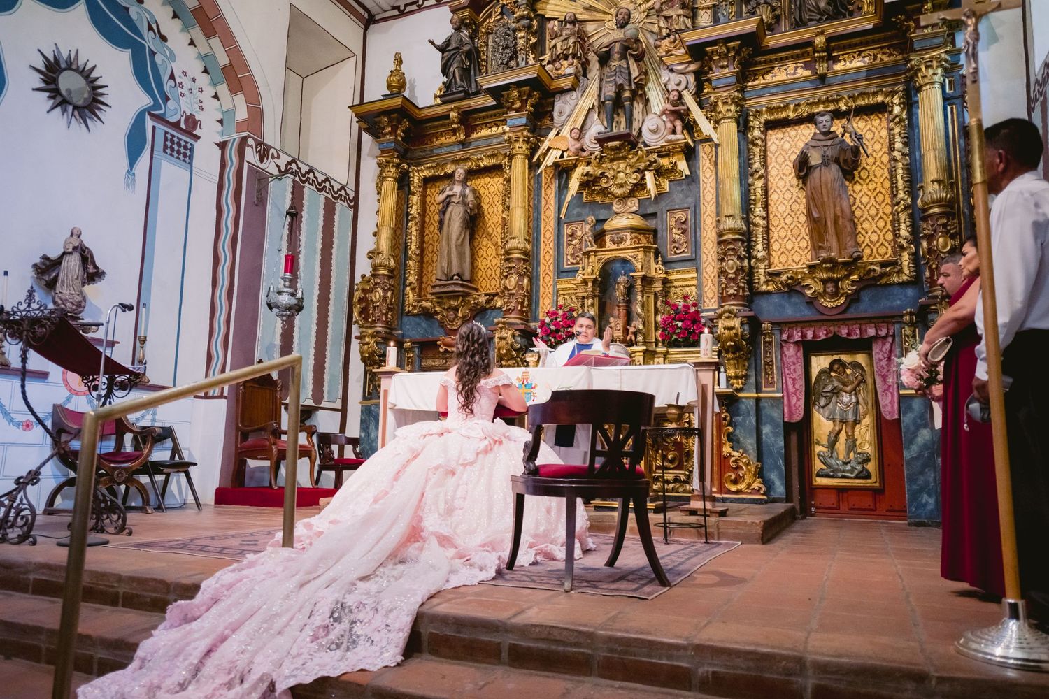 Ornate church interior with golden altar and long pink dress train in foreground.