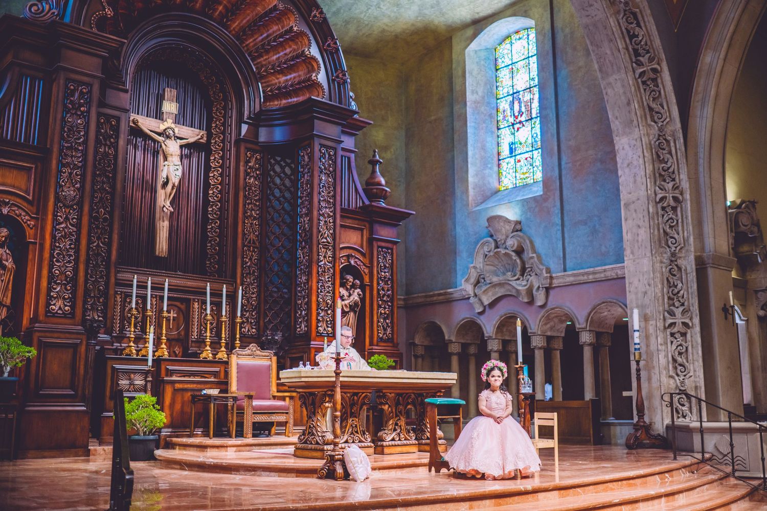 Pink formal dress celebration photography session inside ornate church with stained glass windows.