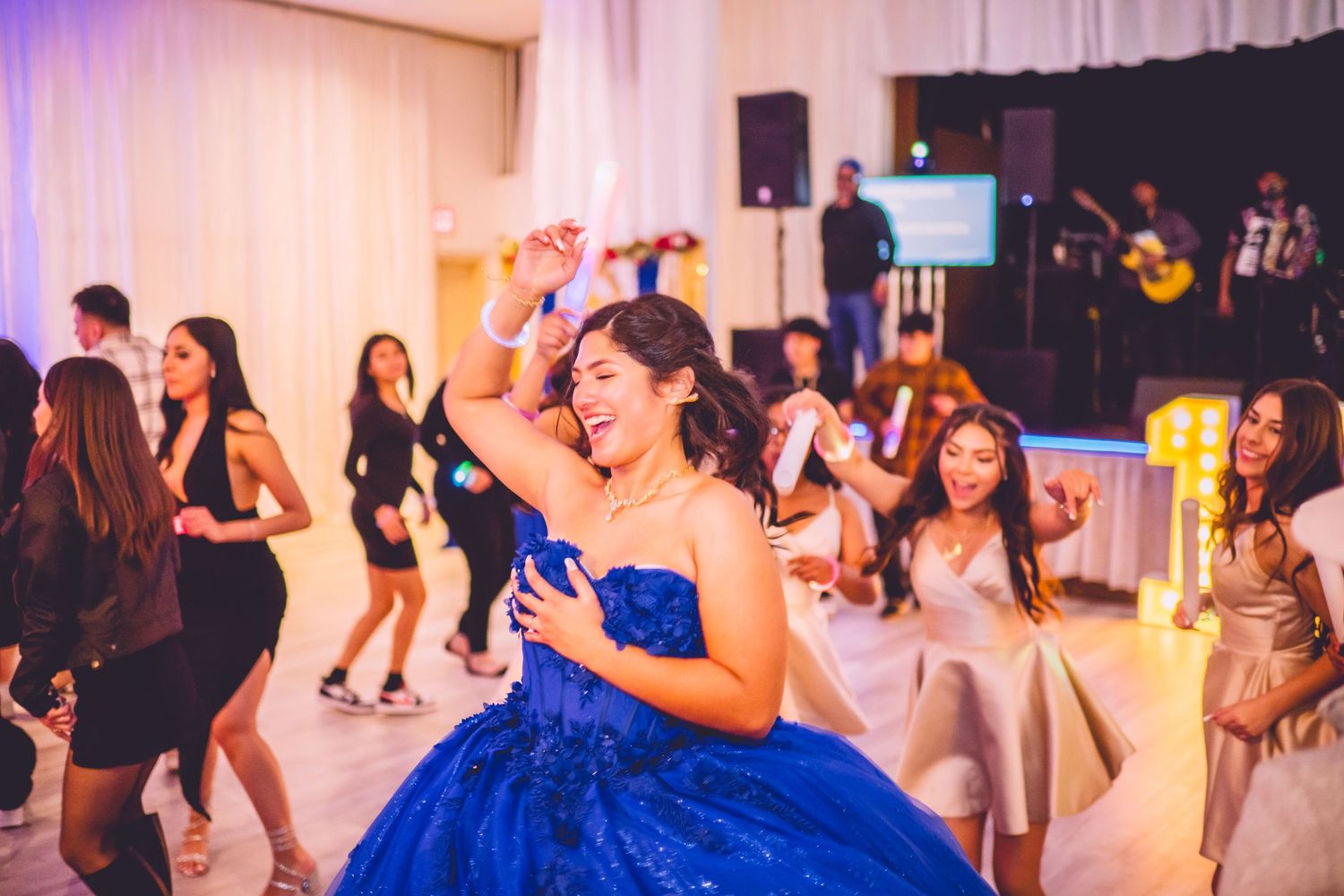 A celebration scene shows a dancer in a blue formal gown twirling on the dance floor while others enjoy the party in the background.