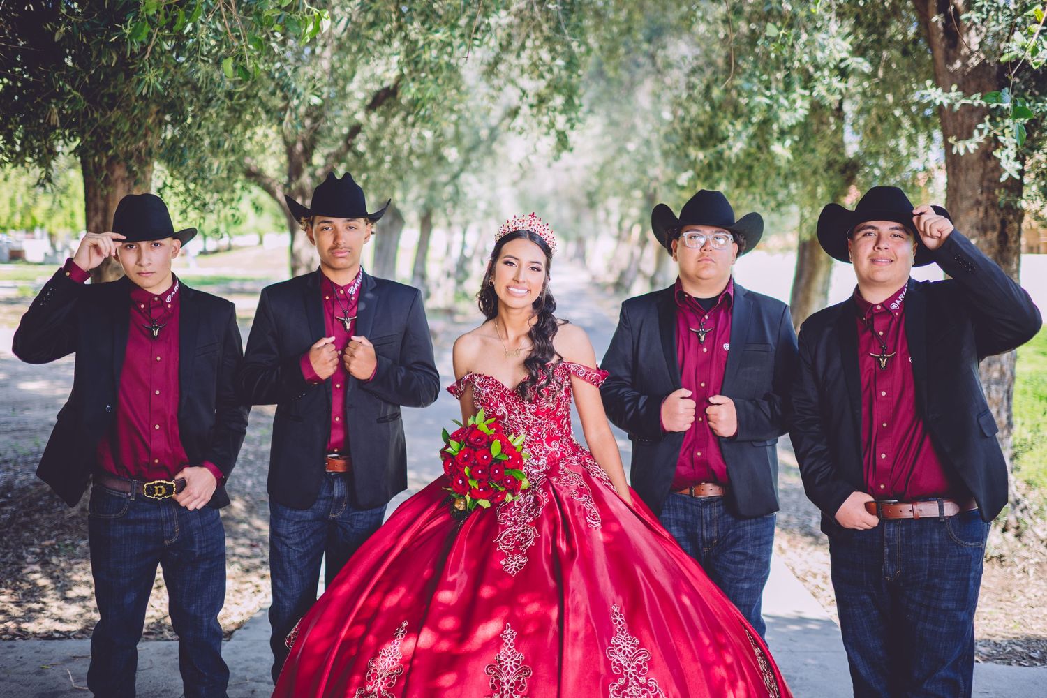 Group in black western attire and red dress pose together outdoors.