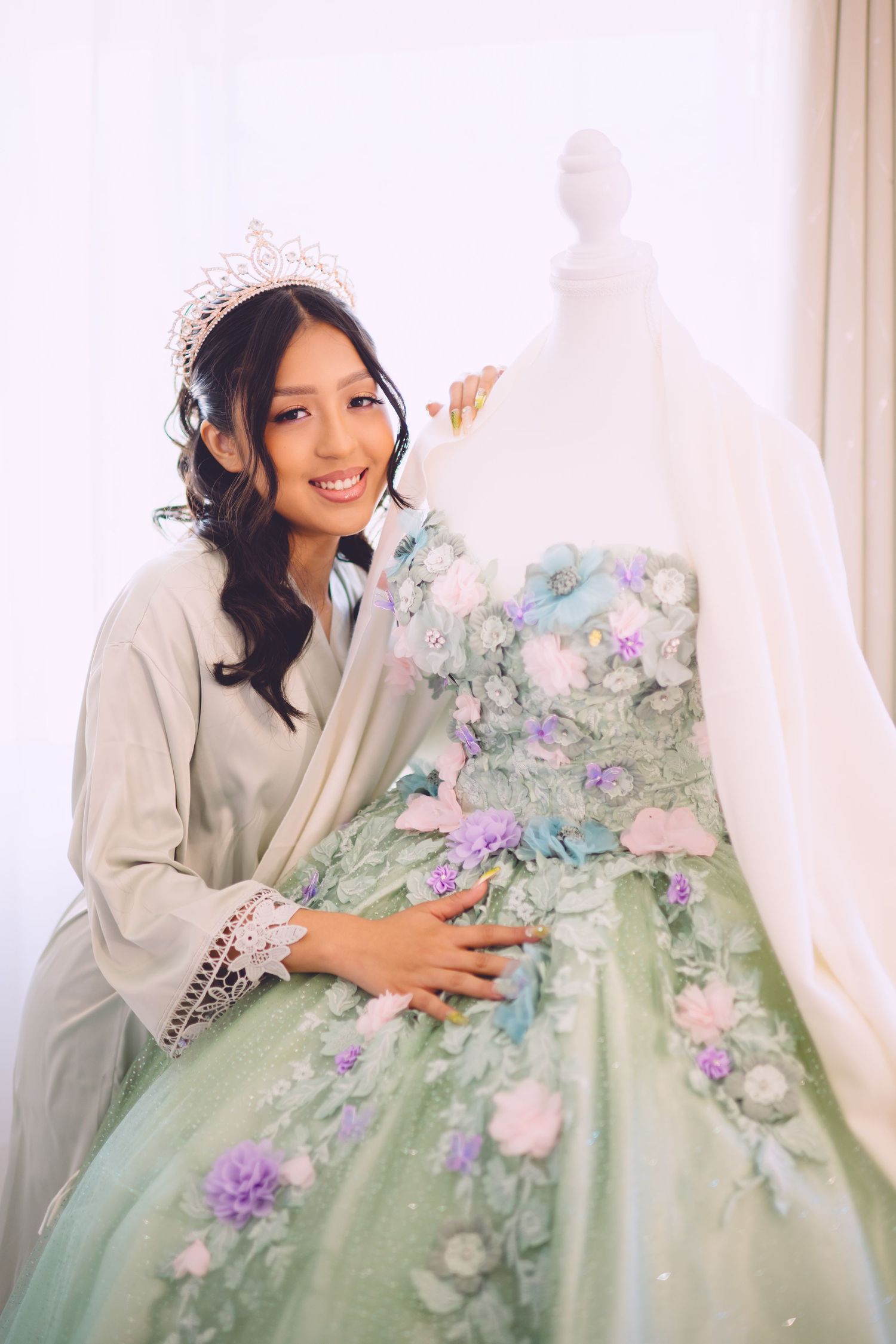 Beautiful mint green formal gown with floral embellishments and delicate pastel blooms displayed before a white background.