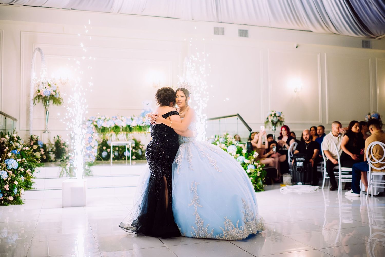 Formal dance between two people in a decorated ballroom with sparkler effects.