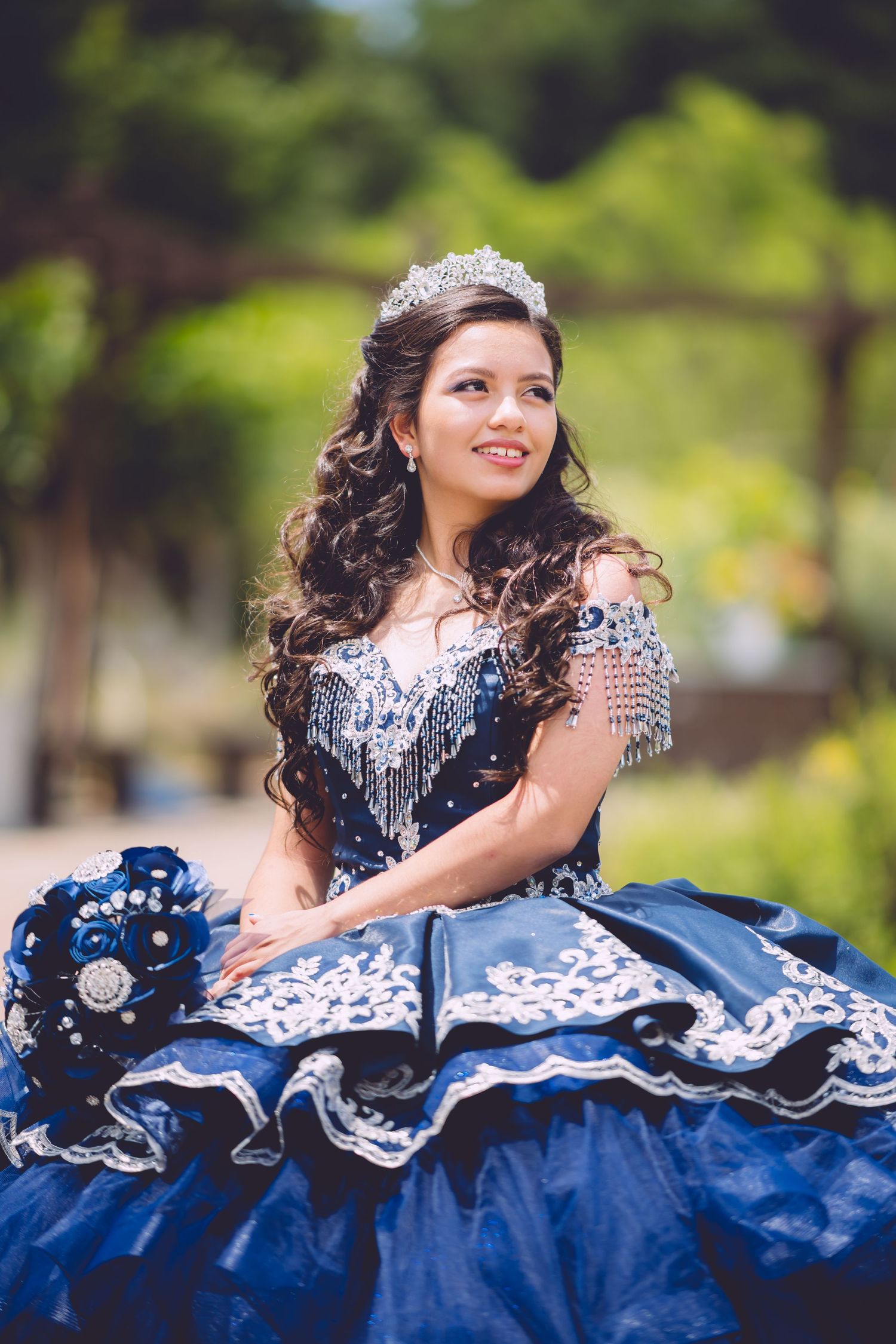 A person wearing a sparkling blue and white quinceañera dress poses outdoors in a series of flowing movement shots.