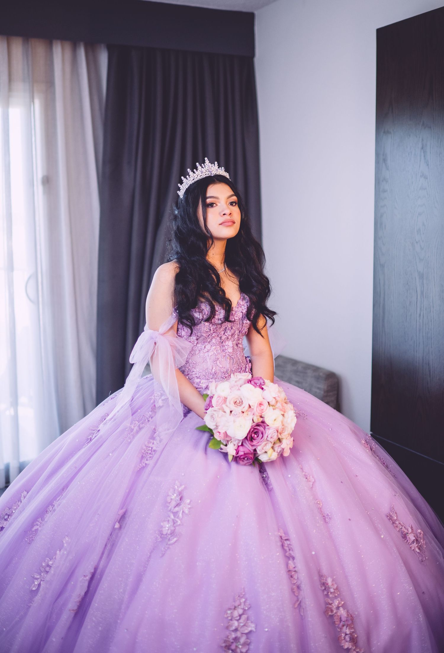 A lavender princess ballgown with delicate floral appliques sparkles in natural light.