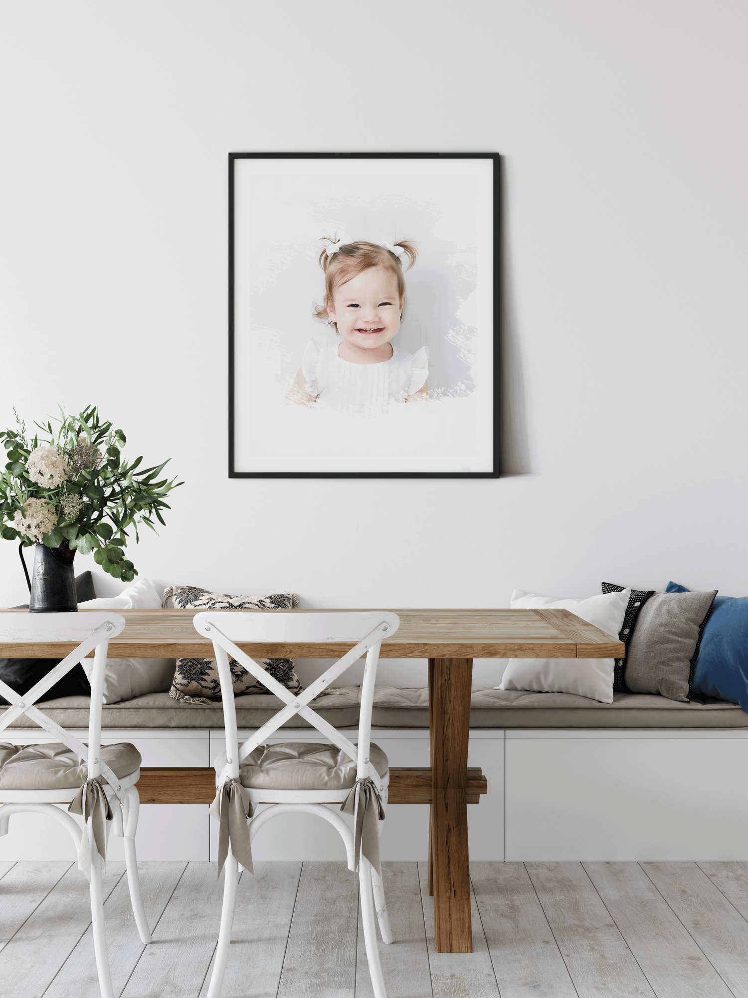 Modern coastal dining space with wooden table, white chairs, built-in bench seating and framed portrait above in minimal style.