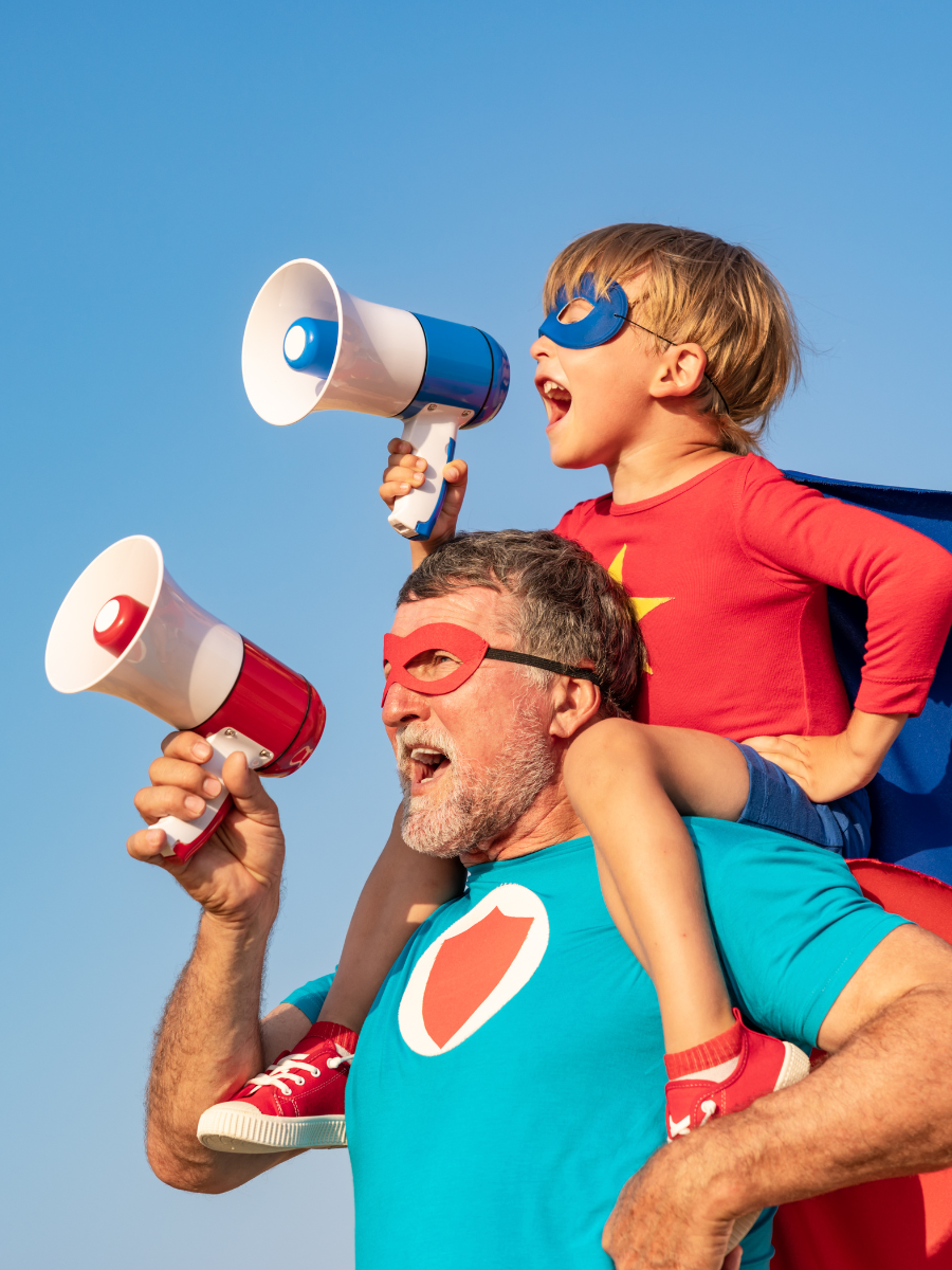 stock photo of man with boy on shoulders both dressed as superheroes