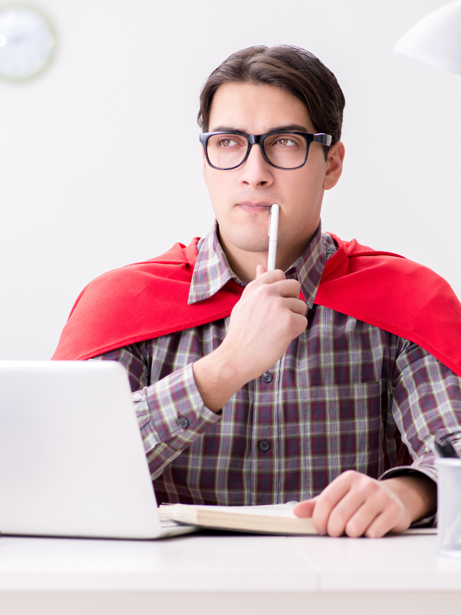 stock photo of man with cape sitting at computer