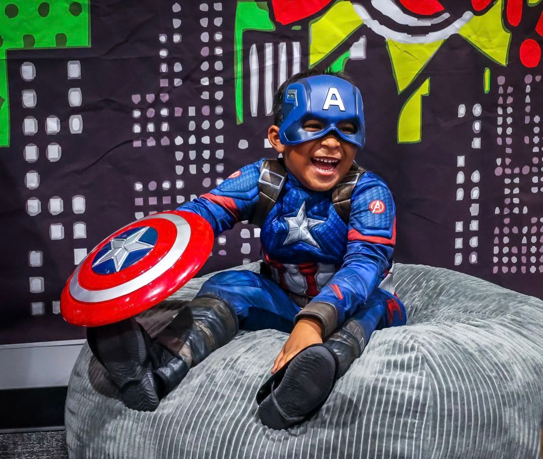 boy in captain america costume laughing and sitting