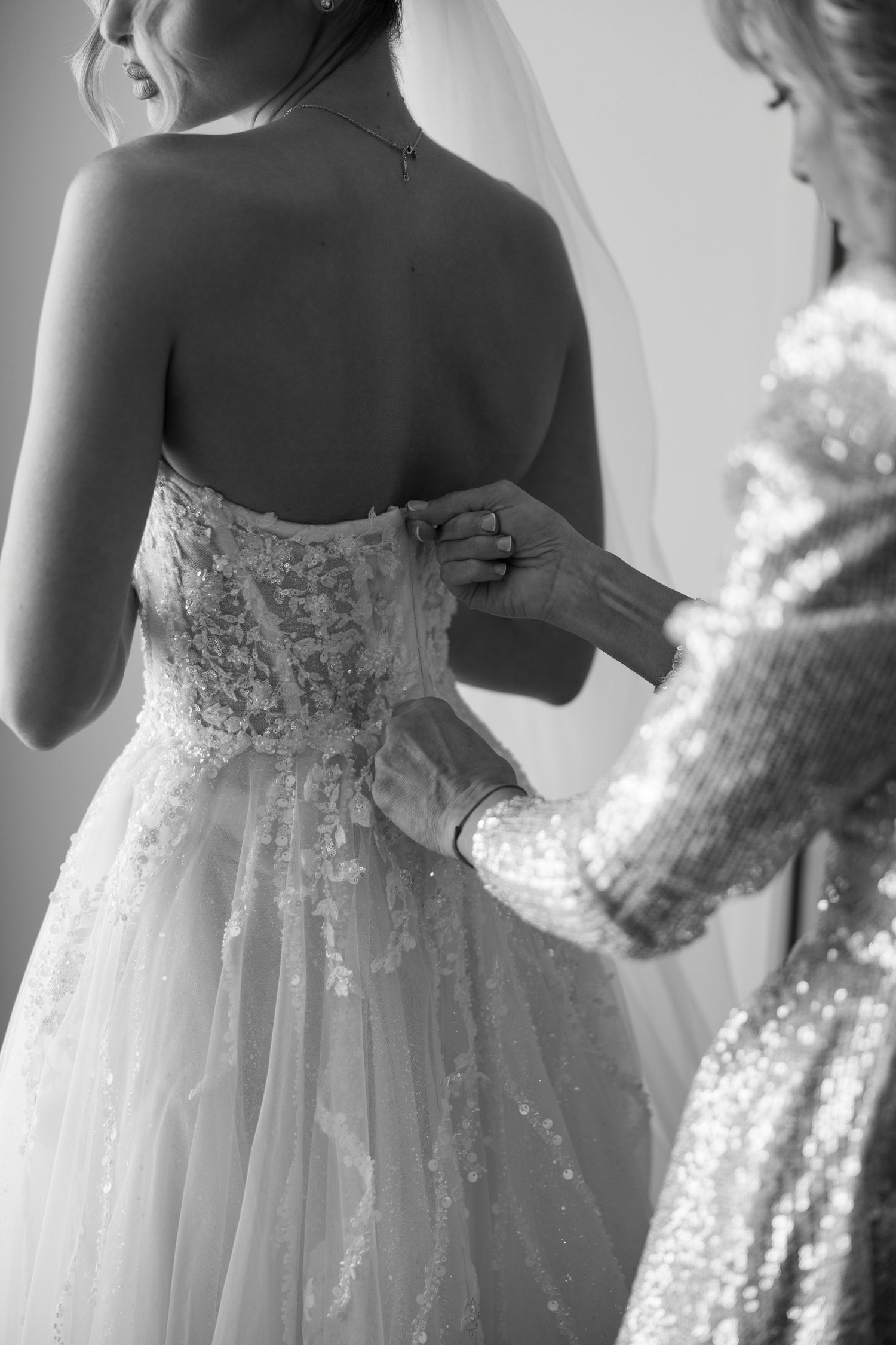 Close-up details of white lace and tulle wedding dresses on display showing intricate beadwork and embellishments.