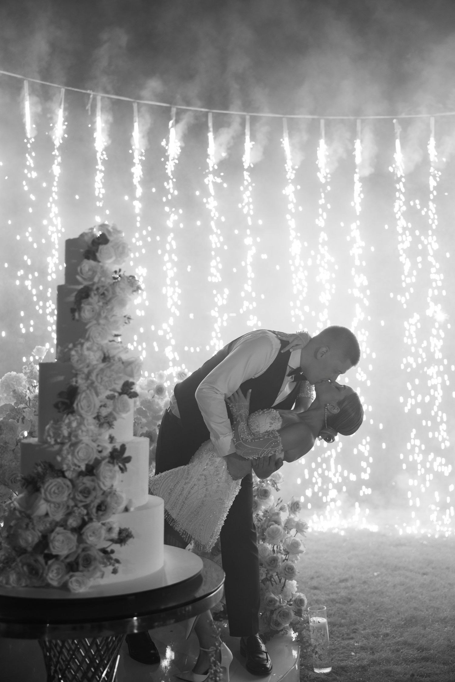 Silhouettes of a couple against cascading fairy light curtains with floral arrangements.