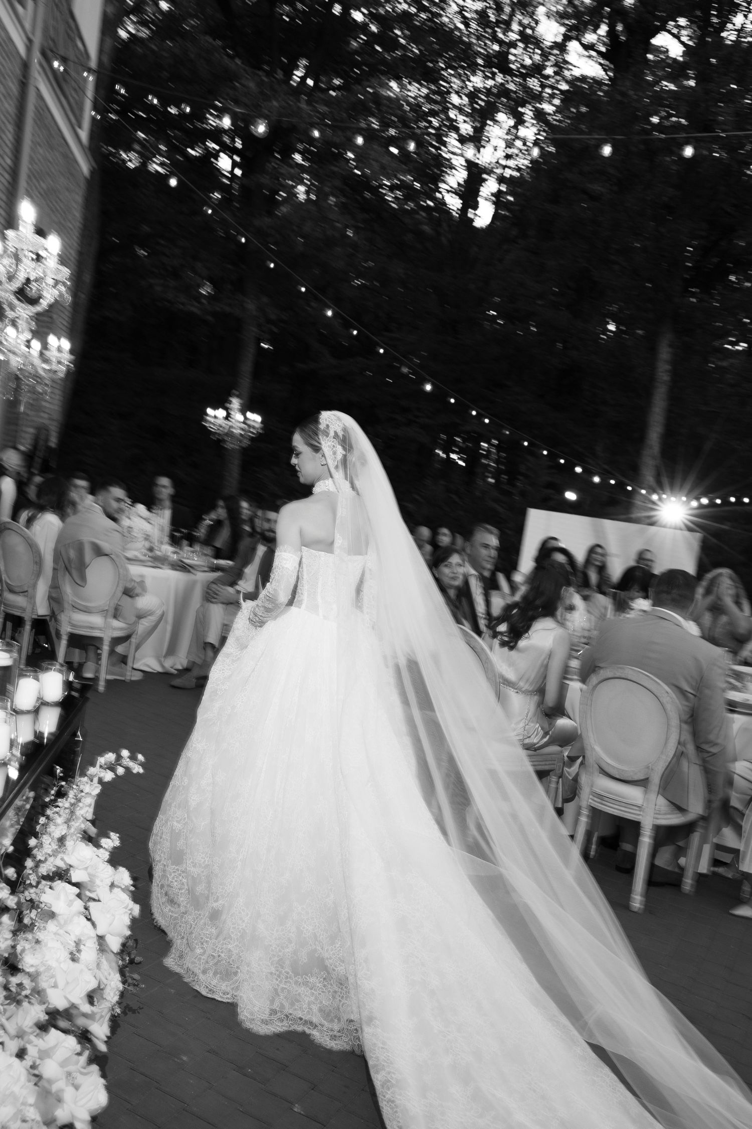 Dramatic black and white photos of bride in flowing gown during outdoor evening celebration.