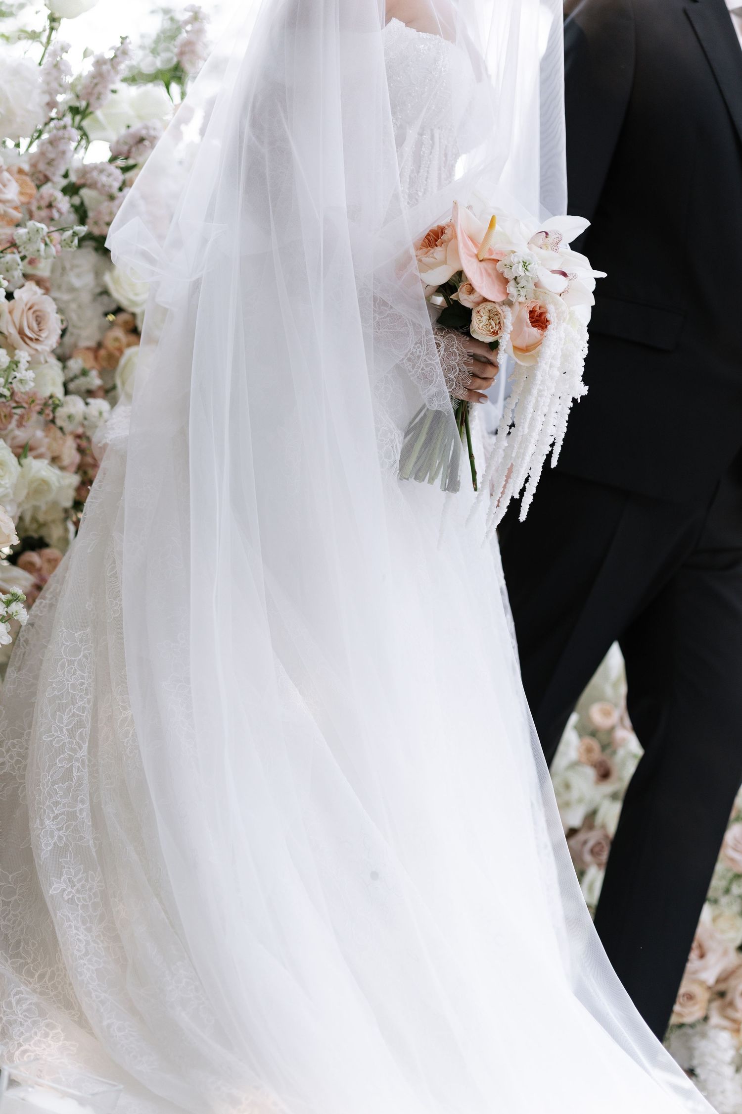 Elegant wedding dress details with flowing white veil and delicate floral accents against a soft background.