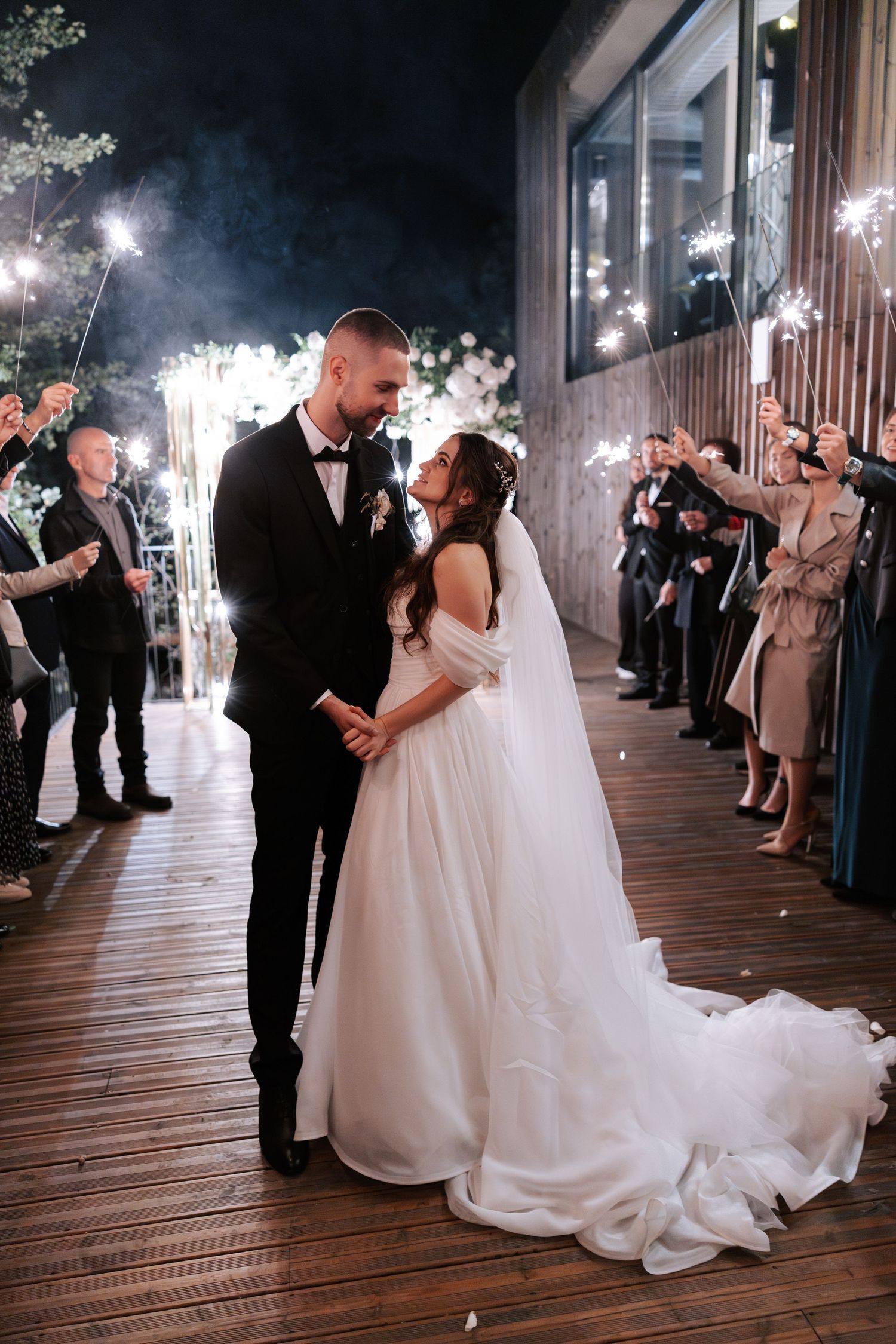 A couple celebrates their wedding day with sparklers creating a magical outdoor atmosphere.