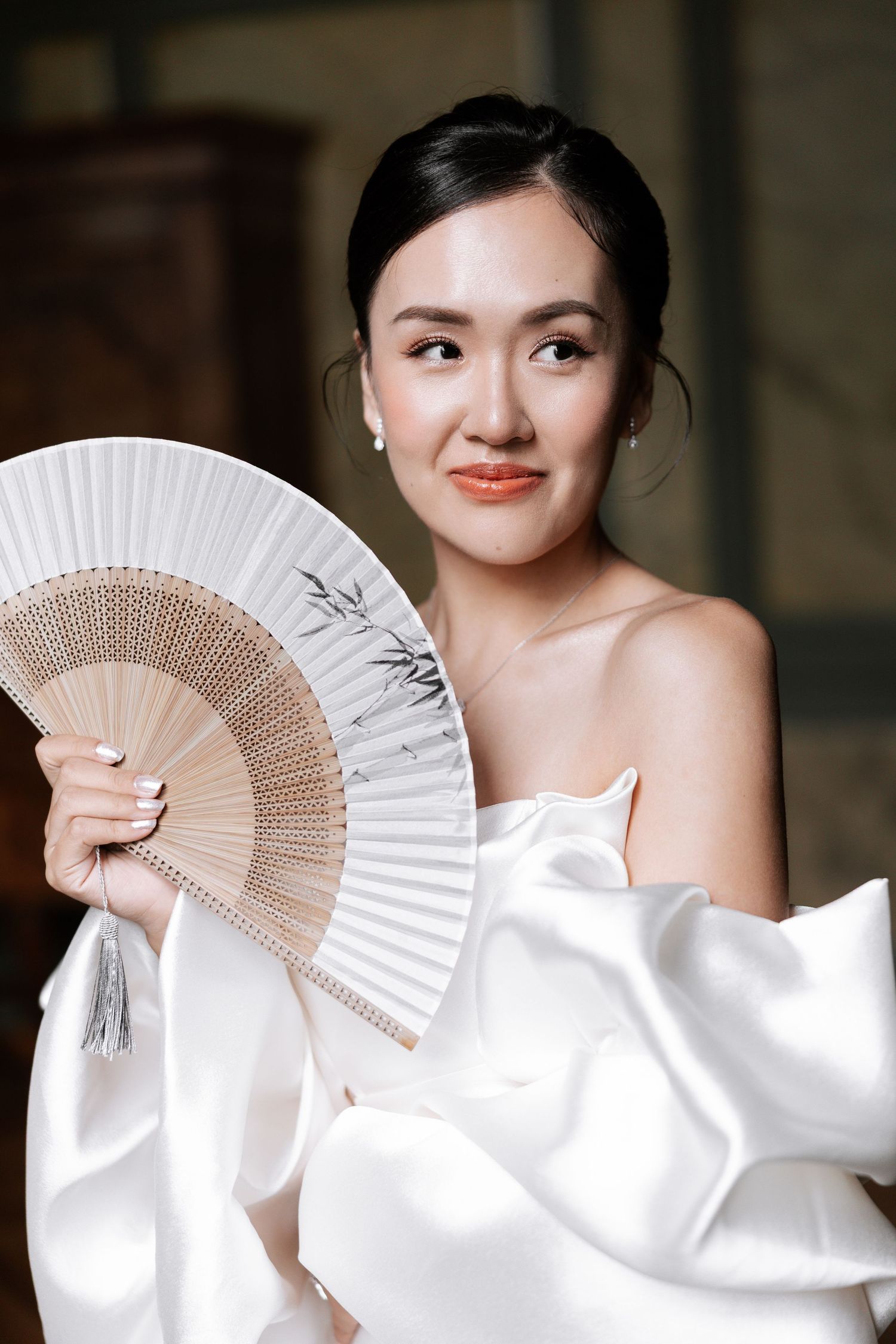 A series of elegant bridal portraits featuring traditional hand fans and flowing white fabric in a soft, natural setting.
