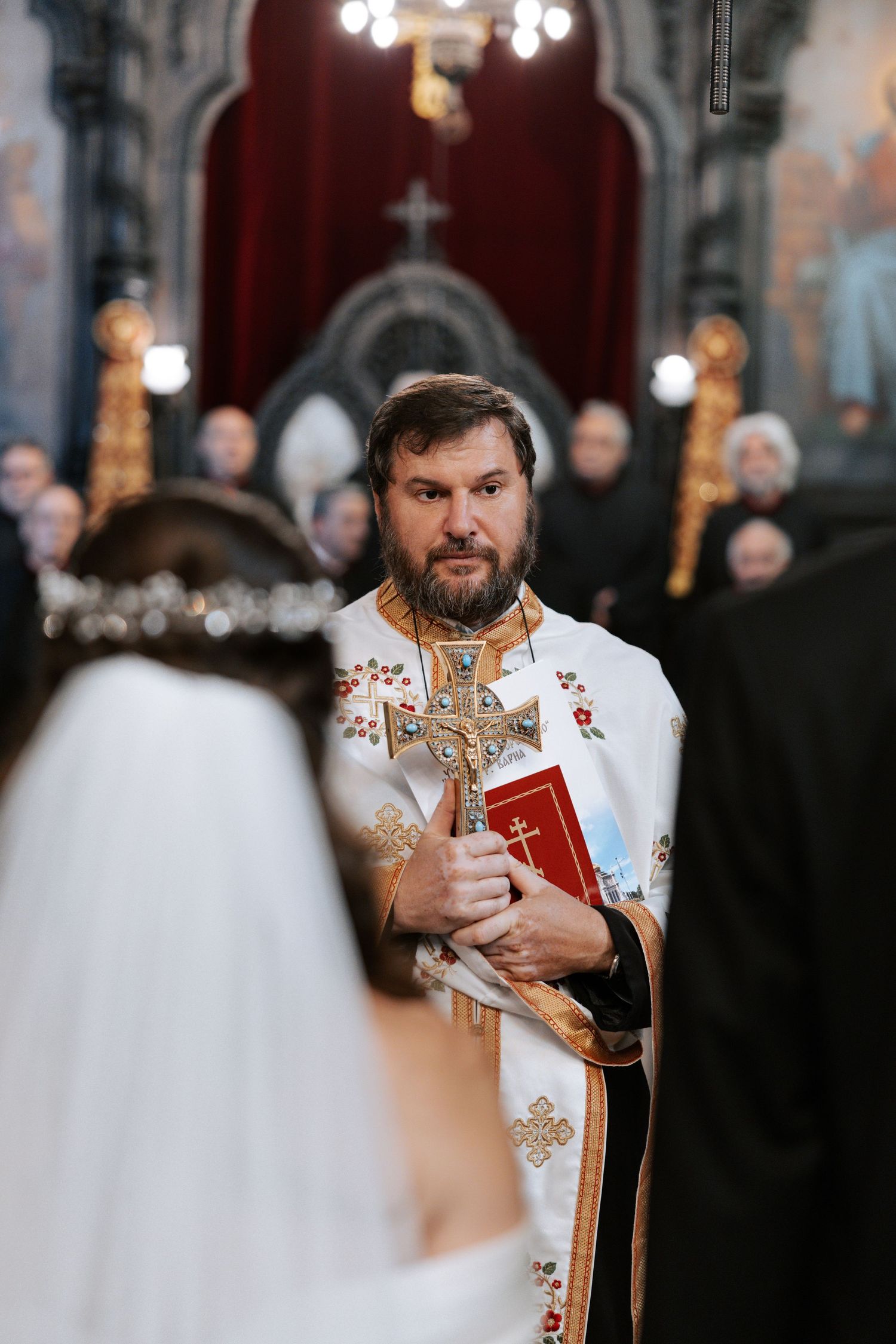 Orthodox priest in embroidered vestments conducts a religious ceremony in an ornate church.