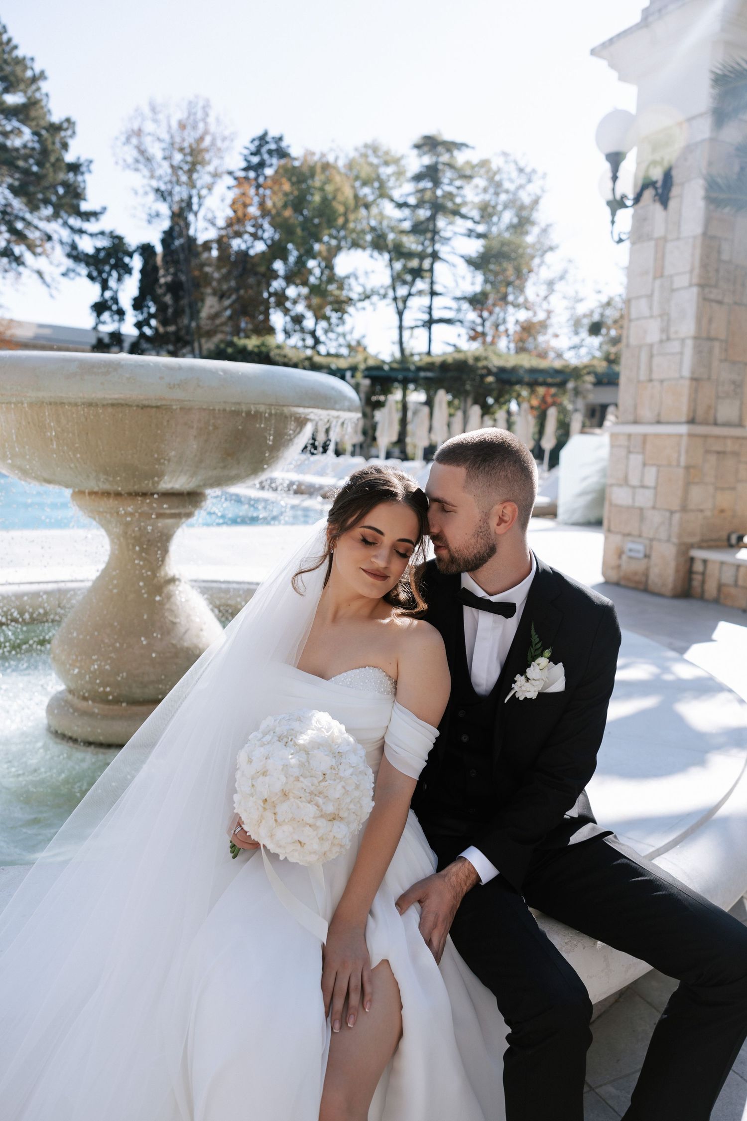 Couple sharing tender moment by fountain during wedding photoshoot.