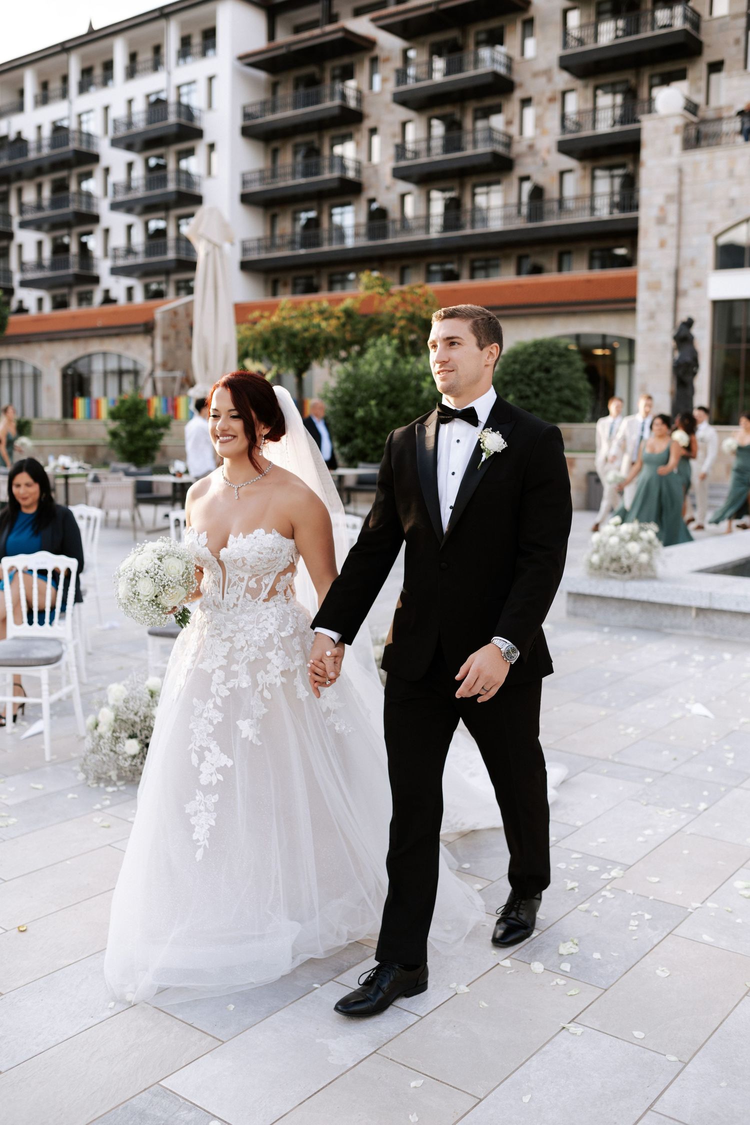 Bride and groom walk hand in hand outside luxury mountain resort.