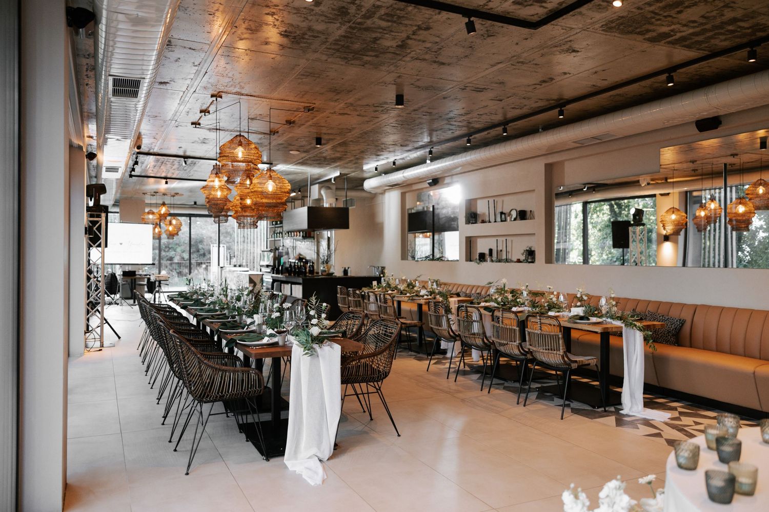 Industrial-chic restaurant space with pendant lighting, brown chairs and leather booth seating.