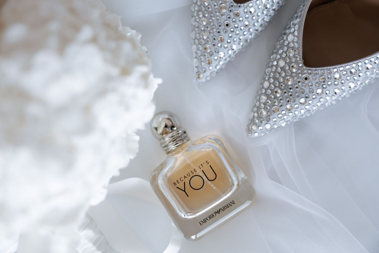 A perfume bottle labeled 'YOU' alongside sparkly wedding shoes and lace details.