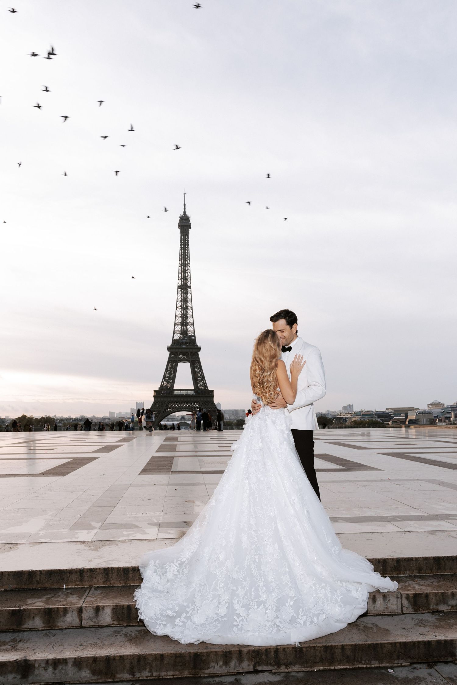 Elegant wedding couple embraces in front of the Eiffel Tower at sunset in Paris.