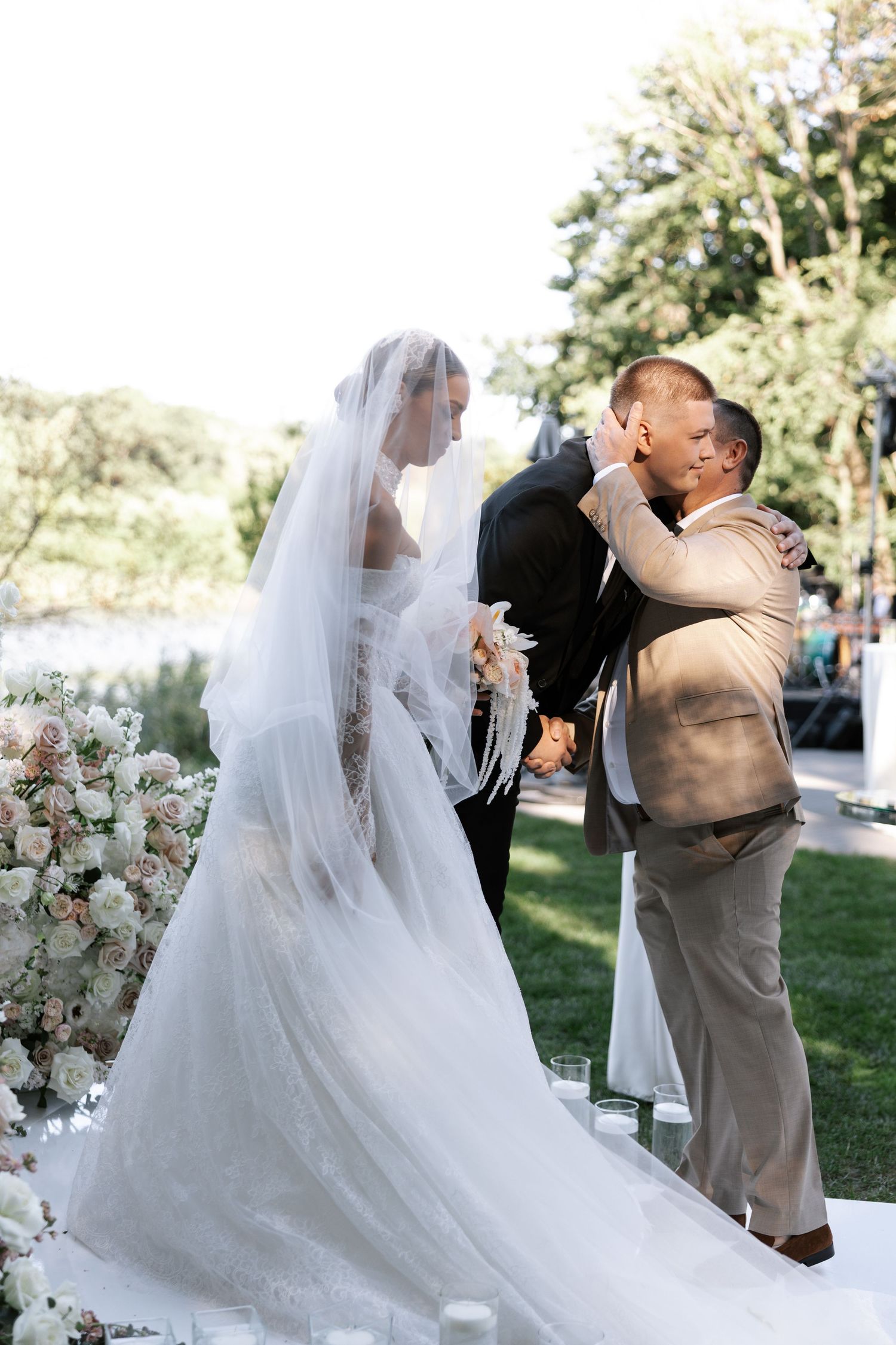 Wedding ceremony moment with flowing white veil and floral decorations in an outdoor setting.