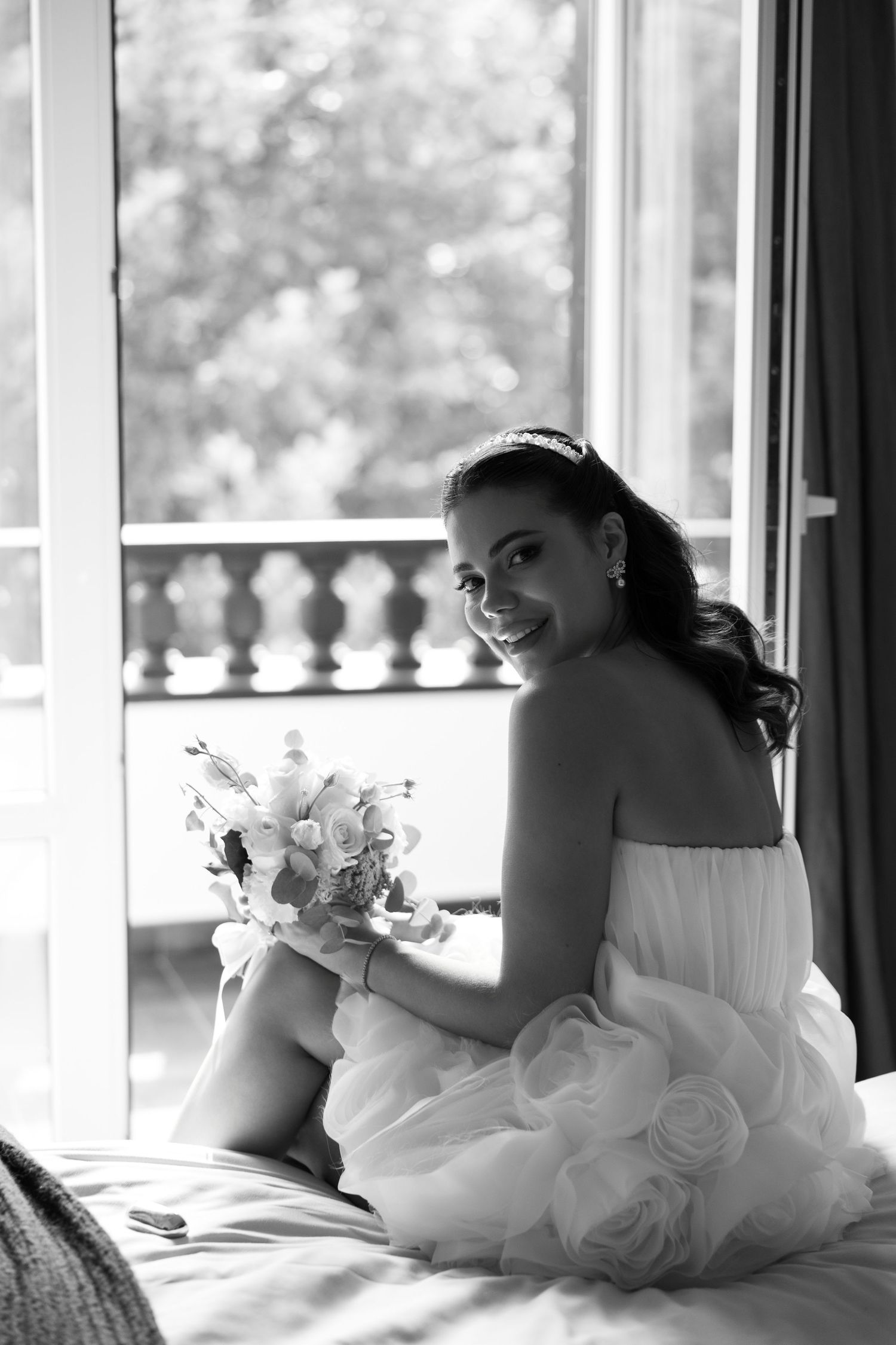A black and white artistic boudoir photo series showing a woman in white dress reclining by sunlit windows.
