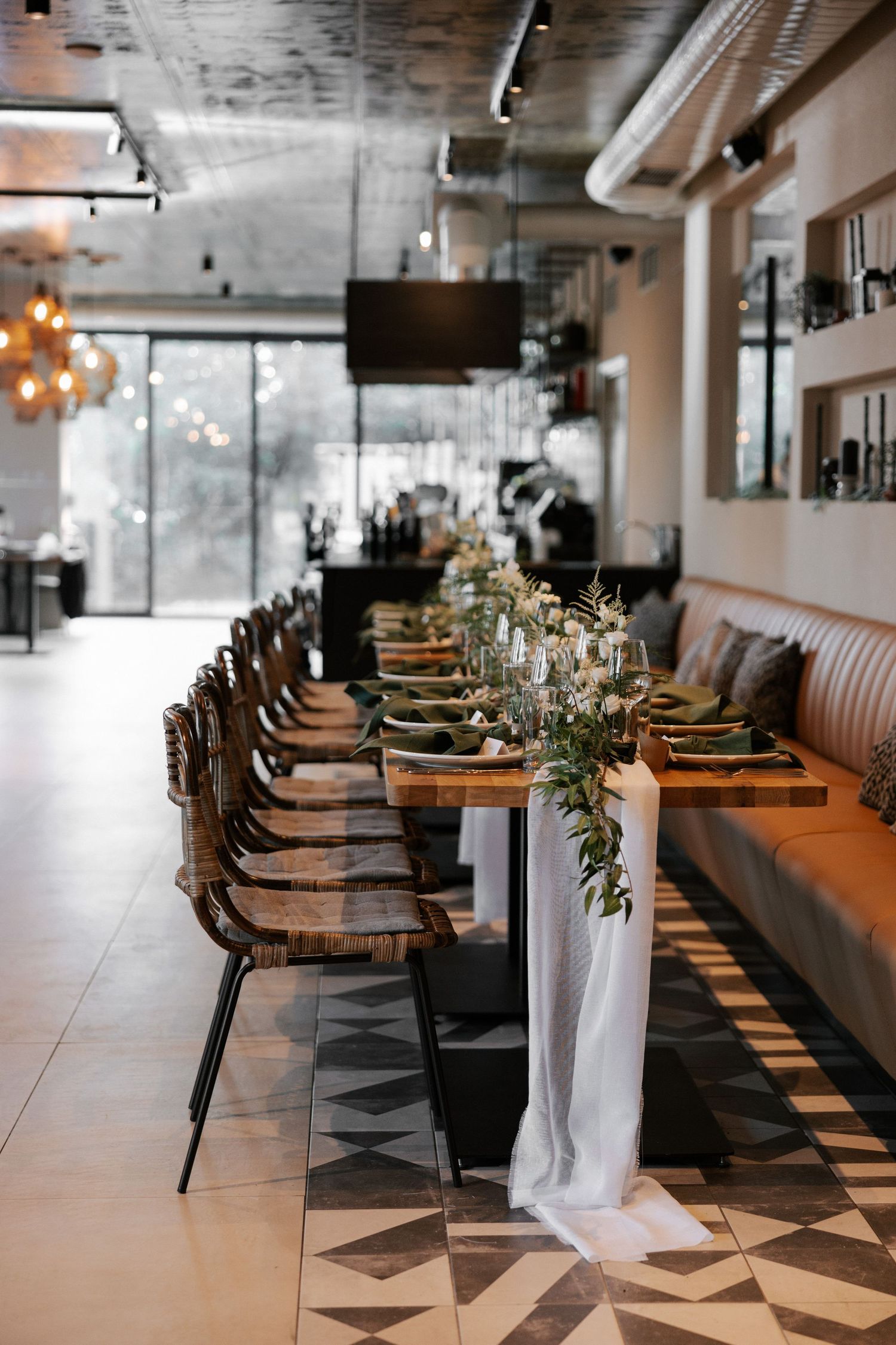 Restaurant dining setup with wooden chairs, orange banquette seating, and white table decorations.