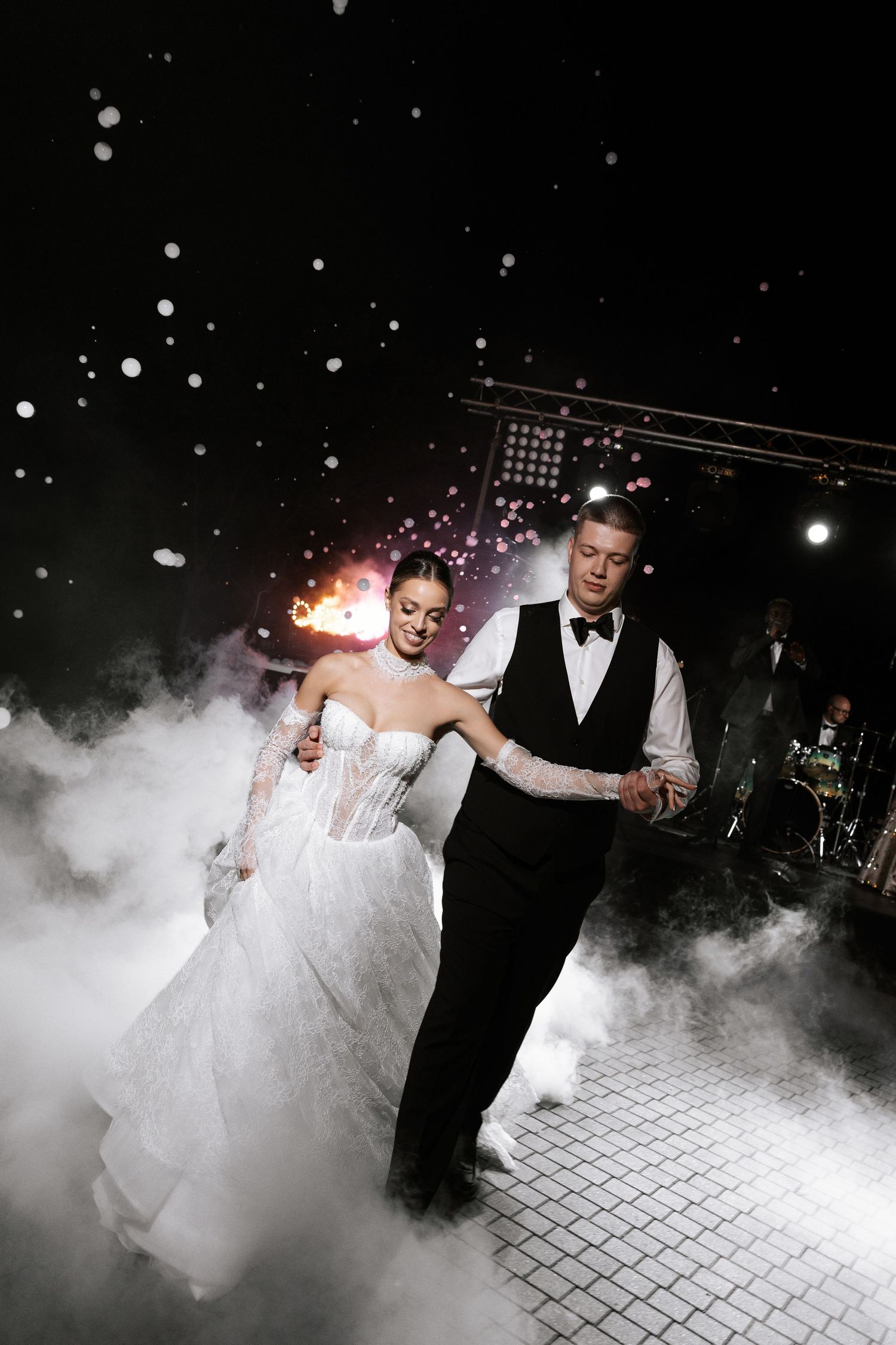 A couple dances amid dramatic fog effects on their wedding dance floor.