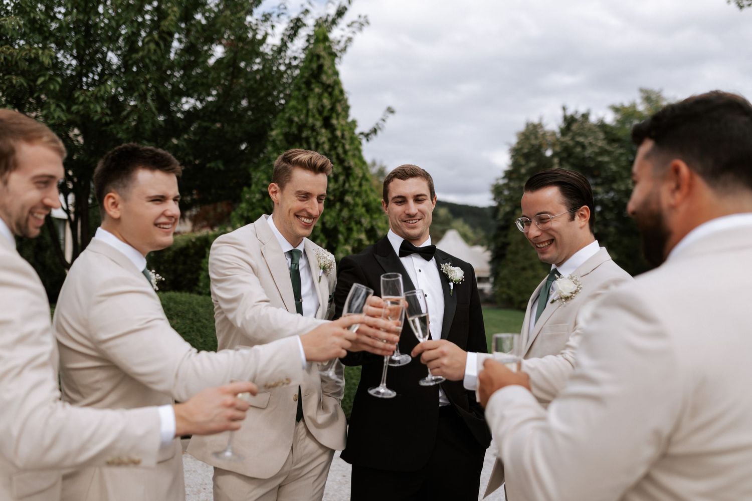 Wedding party raises glasses in a toast on garden path.