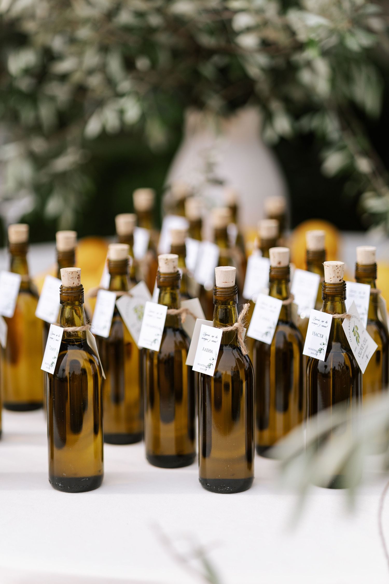Brown glass bottles with small white tags arranged in rows on a white surface for a rustic wedding or event display.