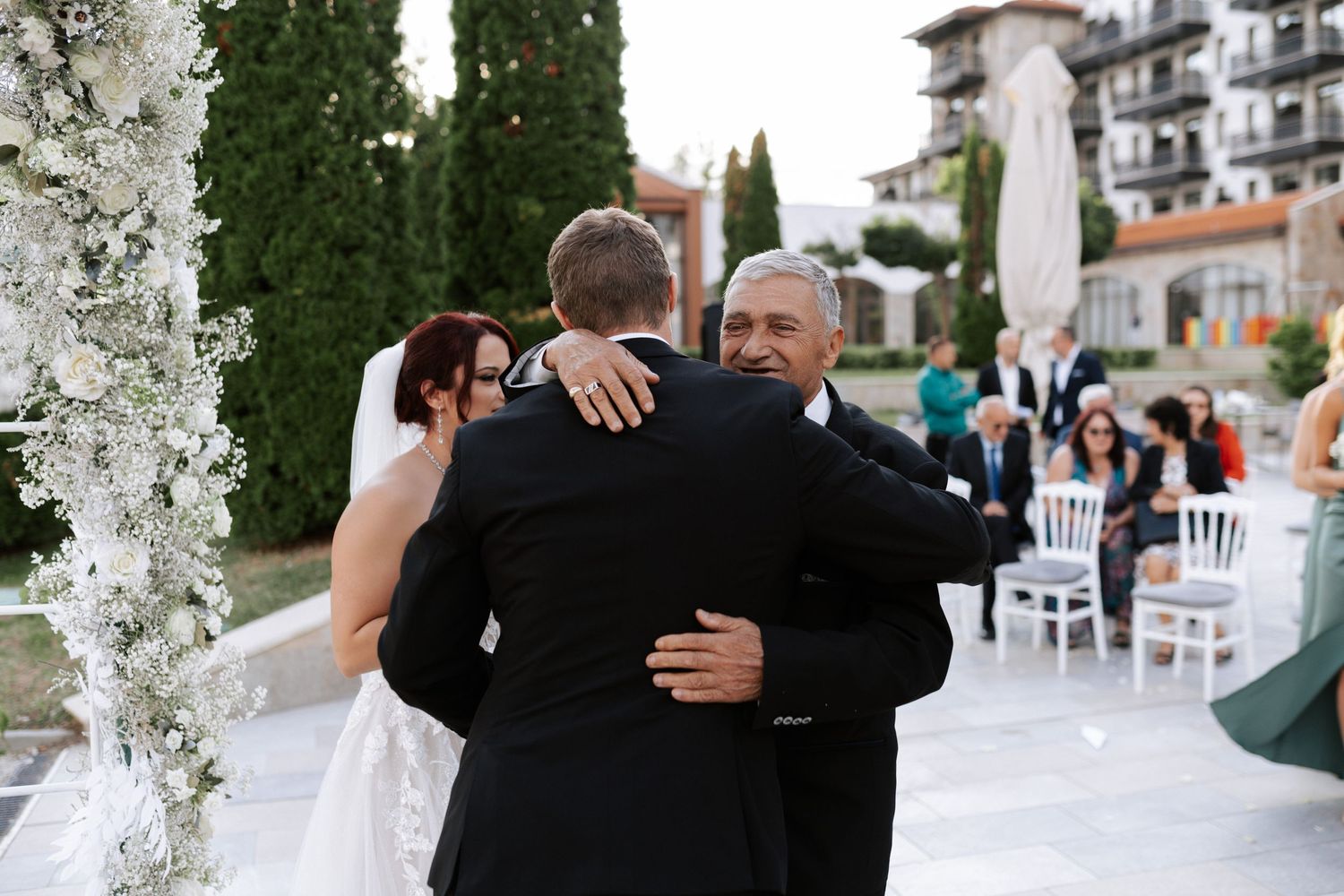 Emotional family embrace during outdoor wedding ceremony.