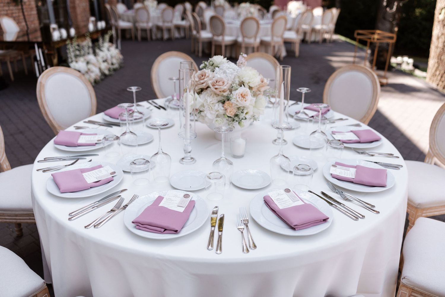 Elegant wedding table setting with mauve accents and white floral centerpiece.