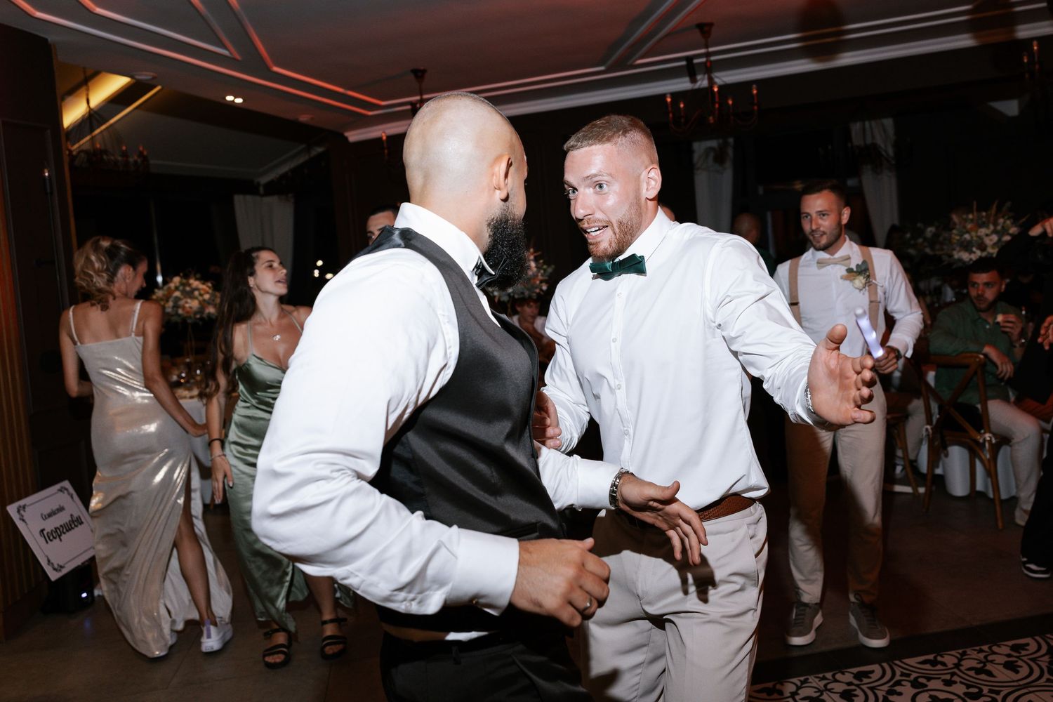 Wedding guests dancing and celebrating together on a dark dance floor at a reception party.