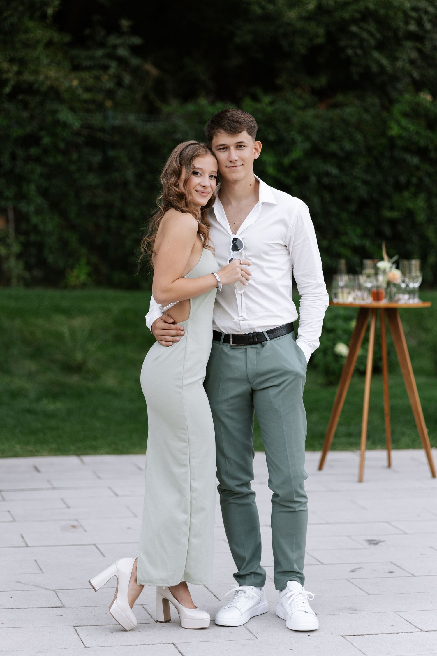 A couple in wedding attire shares intimate moments on a stone patio with decorative furniture in the background.